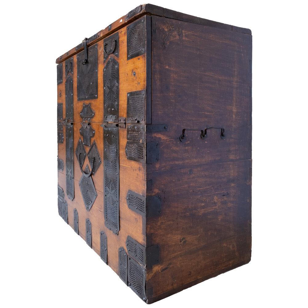 This vintage Korean garment chest is crafted from light honey-colored wood, featuring intricate metal filigree accents. It has two hinged door compartments, offering both storage and timeless style. The beautifully aged patina on the wood and
