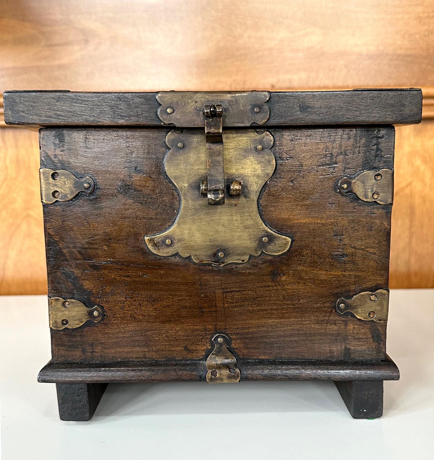 Eine kleine koreanische antike Kiste aus dem späten 19. Jahrhundert der Joseon-Dynastie. Der Kasten in quadratischer Form wurde mit dicken Hartholzbrettern an allen Seiten (anscheinend Ulme) gebaut, mit einem auffälligen Deckel mit Überhang und zwei