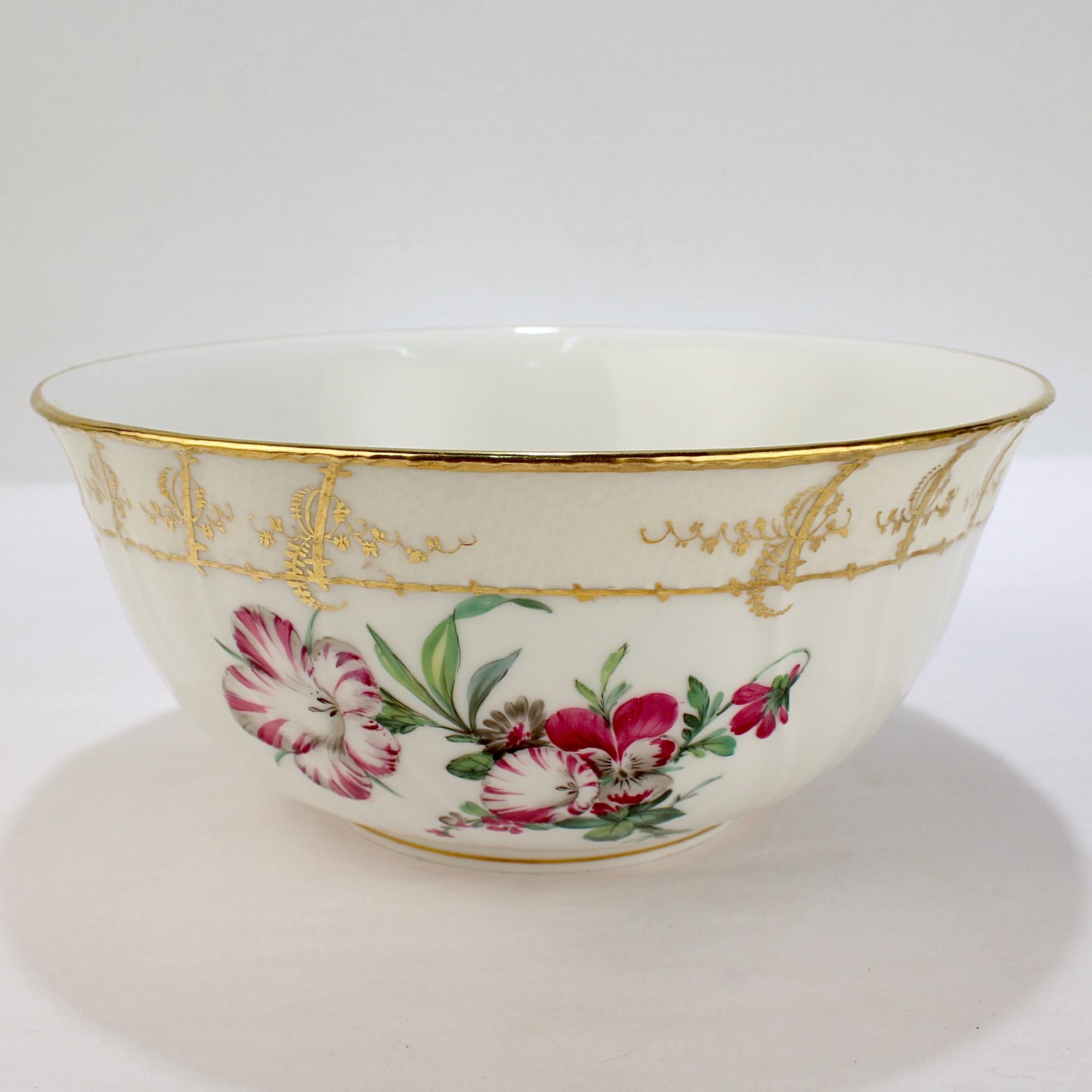 A fine antique porcelain Neuosier pattern fruit bowl.

By KPM (Königliche Porzellan-Manufaktur).

The bowl has a bouquet of purple & white pansies, trumpet flowers, and lilies to the front and a painted yellow border with rich gilding.