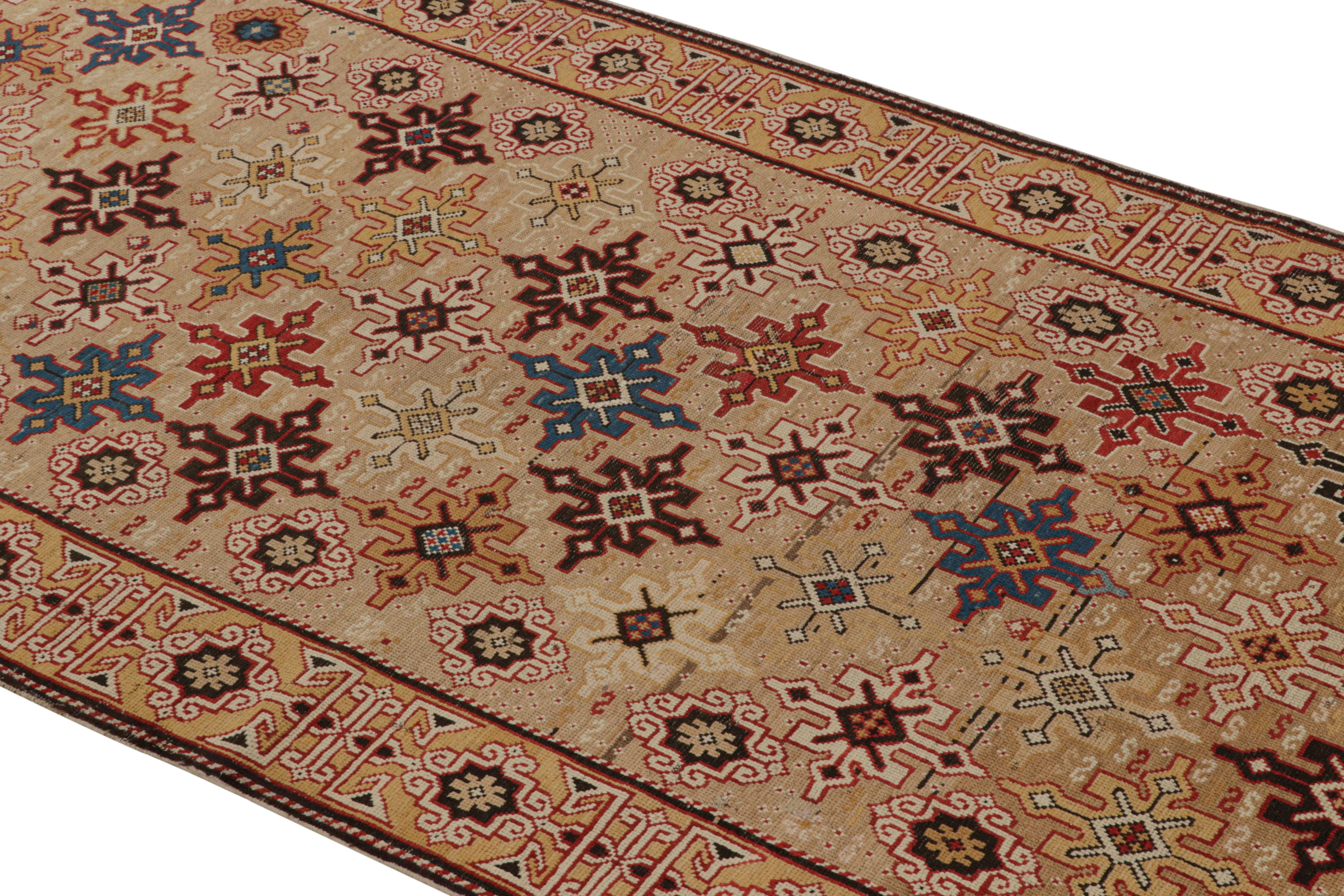 Originating from Russia between 1880-1890, this antique geometric runner enjoys a wrapping border and unique Kuba field design characterized by repeating crimson, blue, black, tan, and golden-yellow eight-pointed stars against an exceptionally rare,