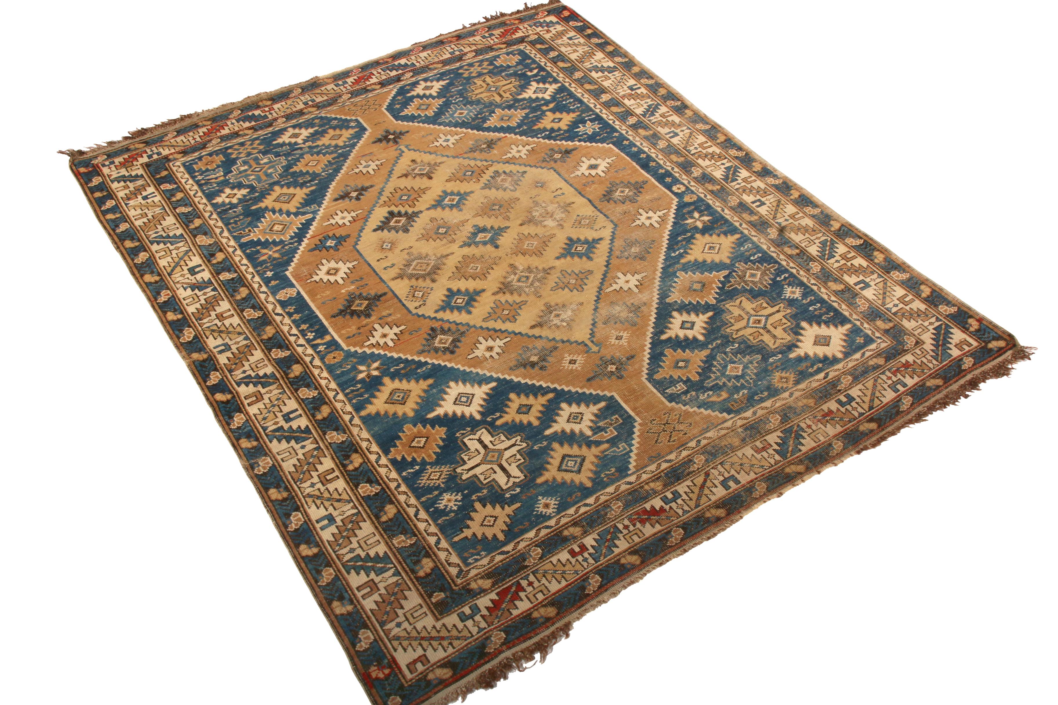Hand knotted in wool originating from Russia between 1910-1920, this antique Kuba rug enjoys a celebrated take on traditional colorway hues this time-honored rug family favors—a play of rich beige brown and abrashed blue bringing out the meticulous