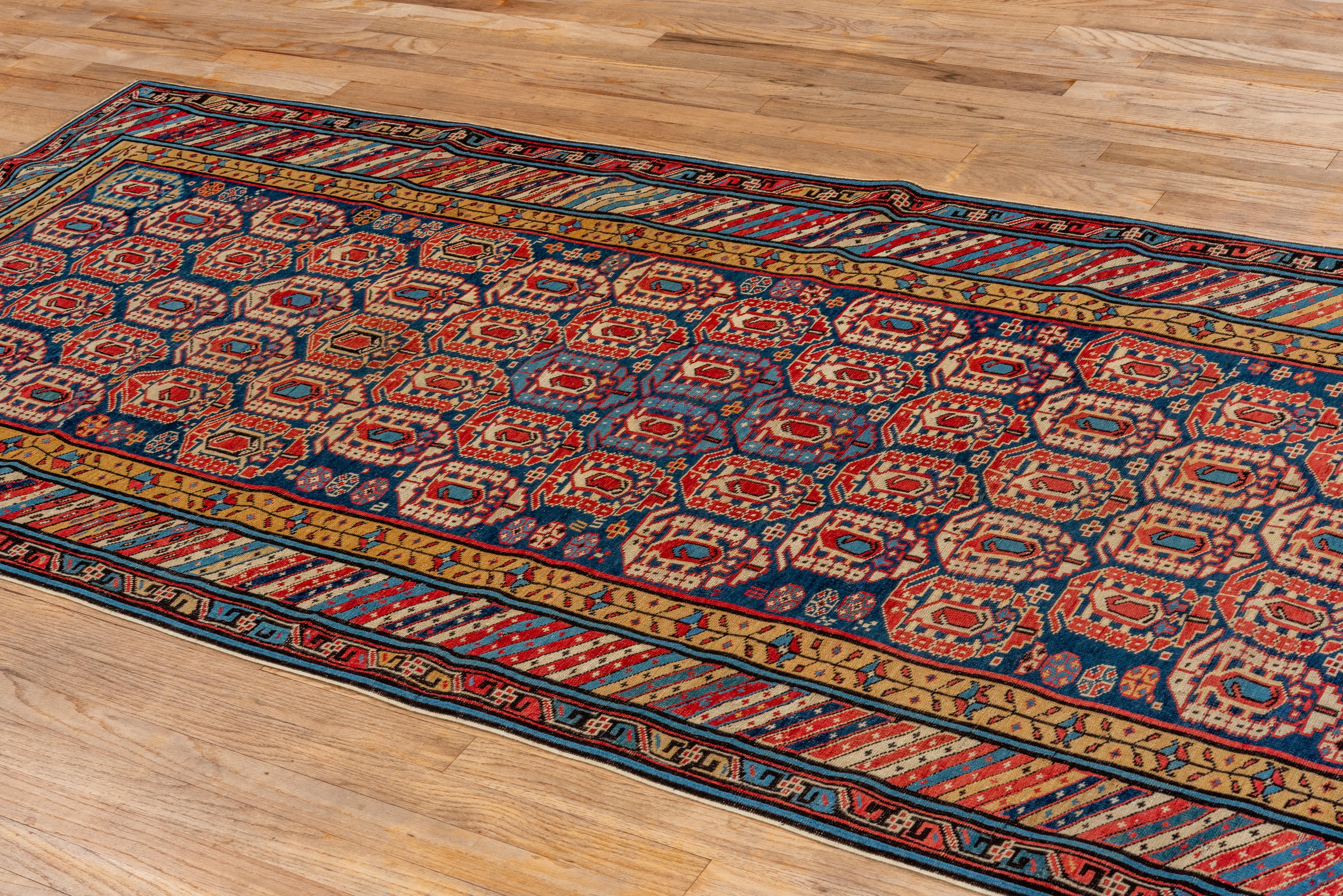 This antique Kuba rug features a mesmerizing allover pattern of latch-hook medallions arranged in tight, rhythmic rows across a rich navy ground. Accents of crimson, ivory, sky blue, and saffron create a layered and intricate visual field, typical