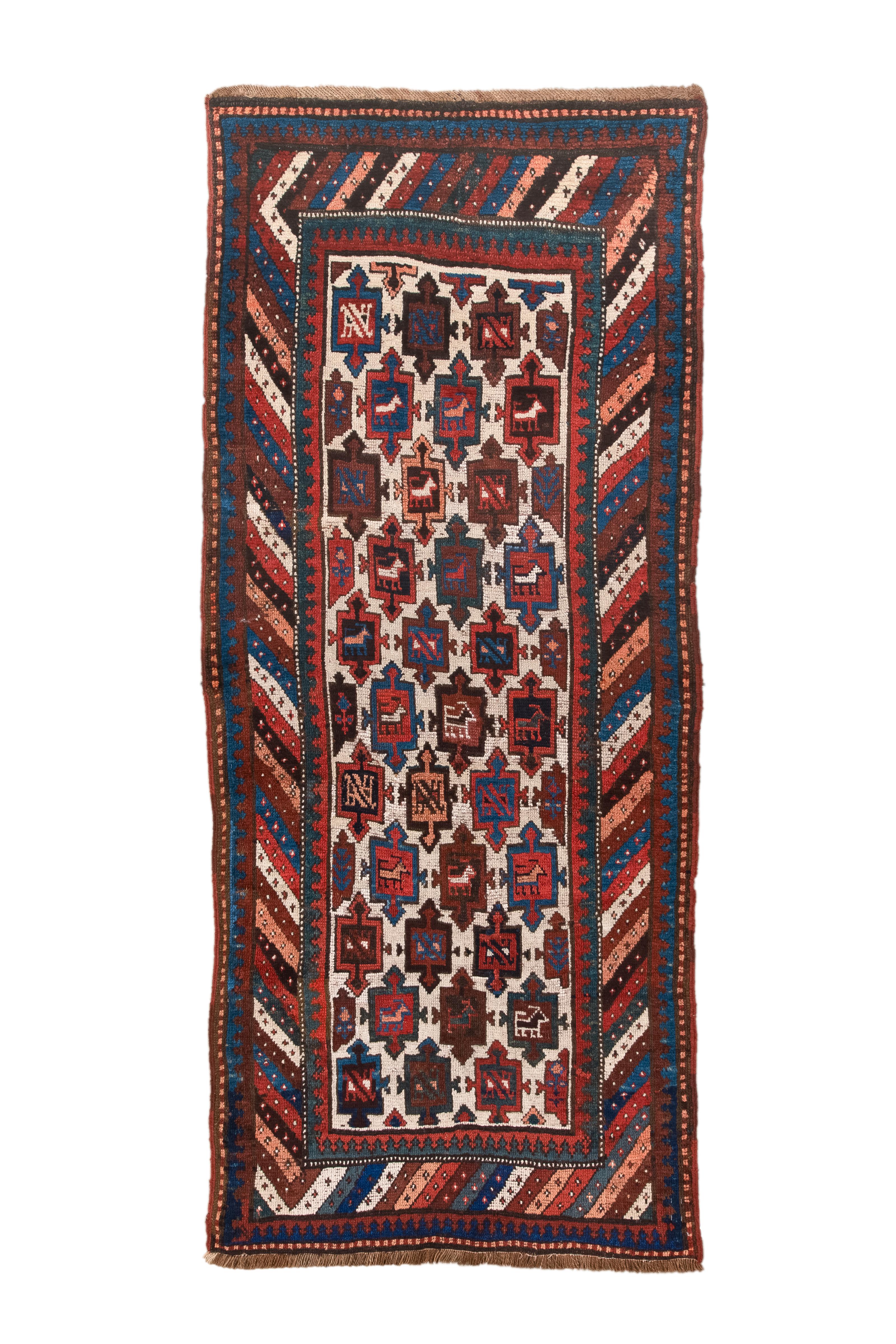 Realizzato nel 1910, questo antico tappeto curdo svela un racconto geometrico in marmo e ossido rosso. La sua tela rettangolare è ornata da intricati motivi geometrici, ognuno dei quali è un pezzo di precisione. Un armonioso gioco di forme si