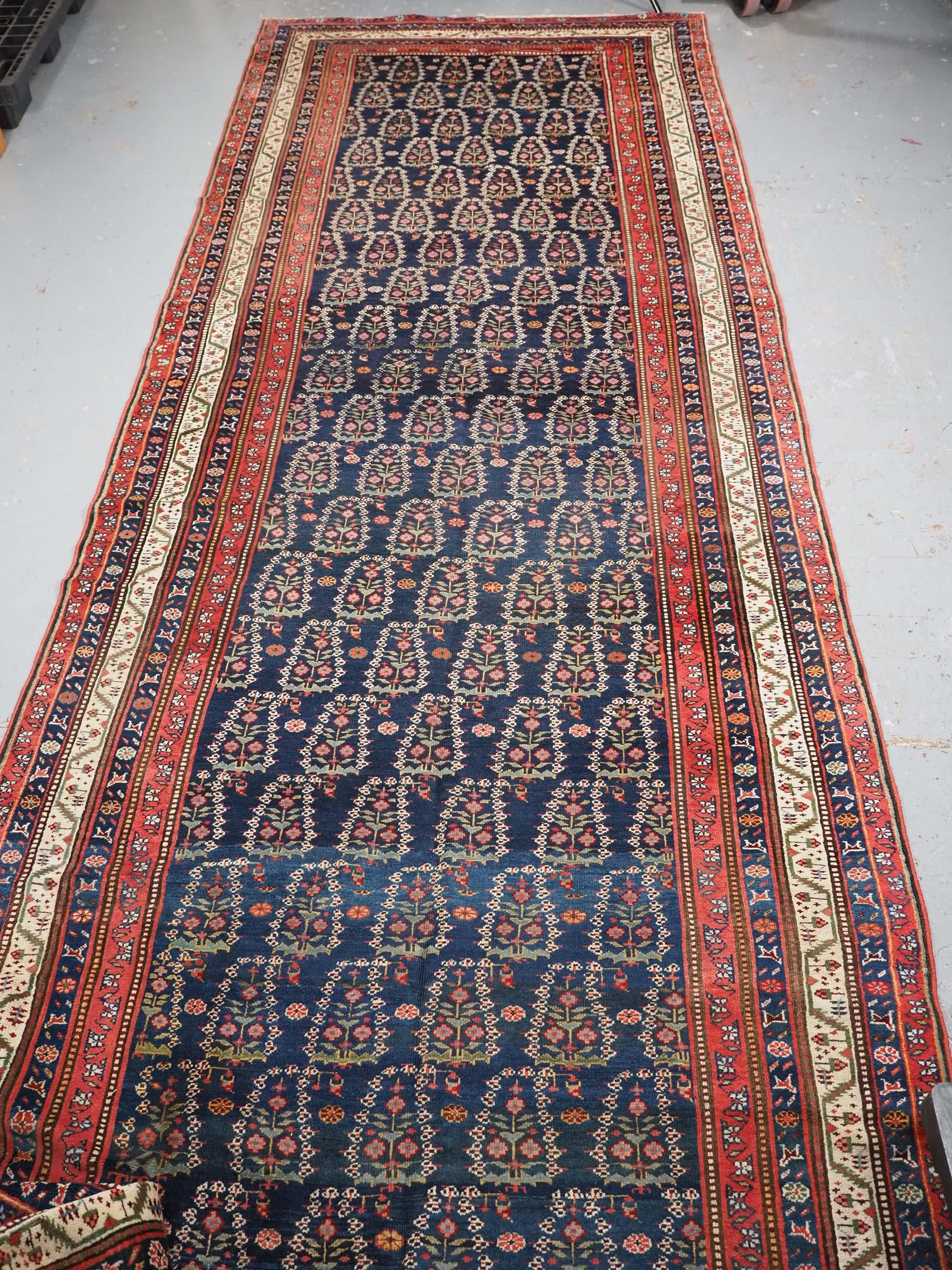 
Taille : 520 x 160 cm.

Tapis kelleh kurde ancien ou grand chemin de couloir avec motif boteh sur toute sa surface.

Circa 1900.

Le tapis présente un motif floral boteh sur un fond bleu indigo foncé. Les boteh sont magnifiquement dessinés avec de