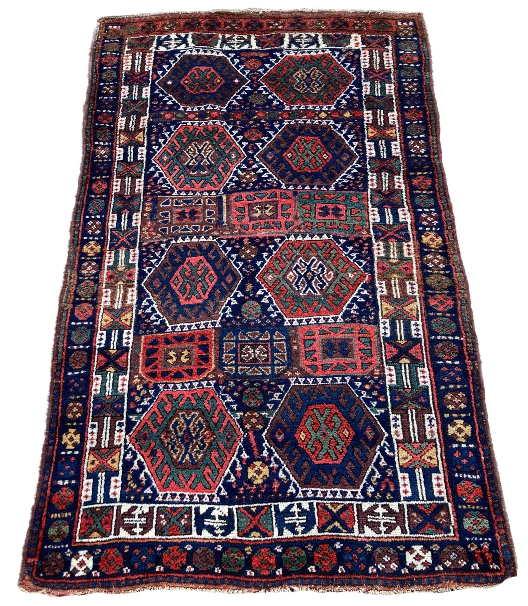 A wonderful antique Kurdish rug, handwoven circa 1900. The rug features an all over geometrical design on a deep indigo field and ivory border. Woven with soft velvety wool and beautiful secondary colours of greens, reds and golds. A great example