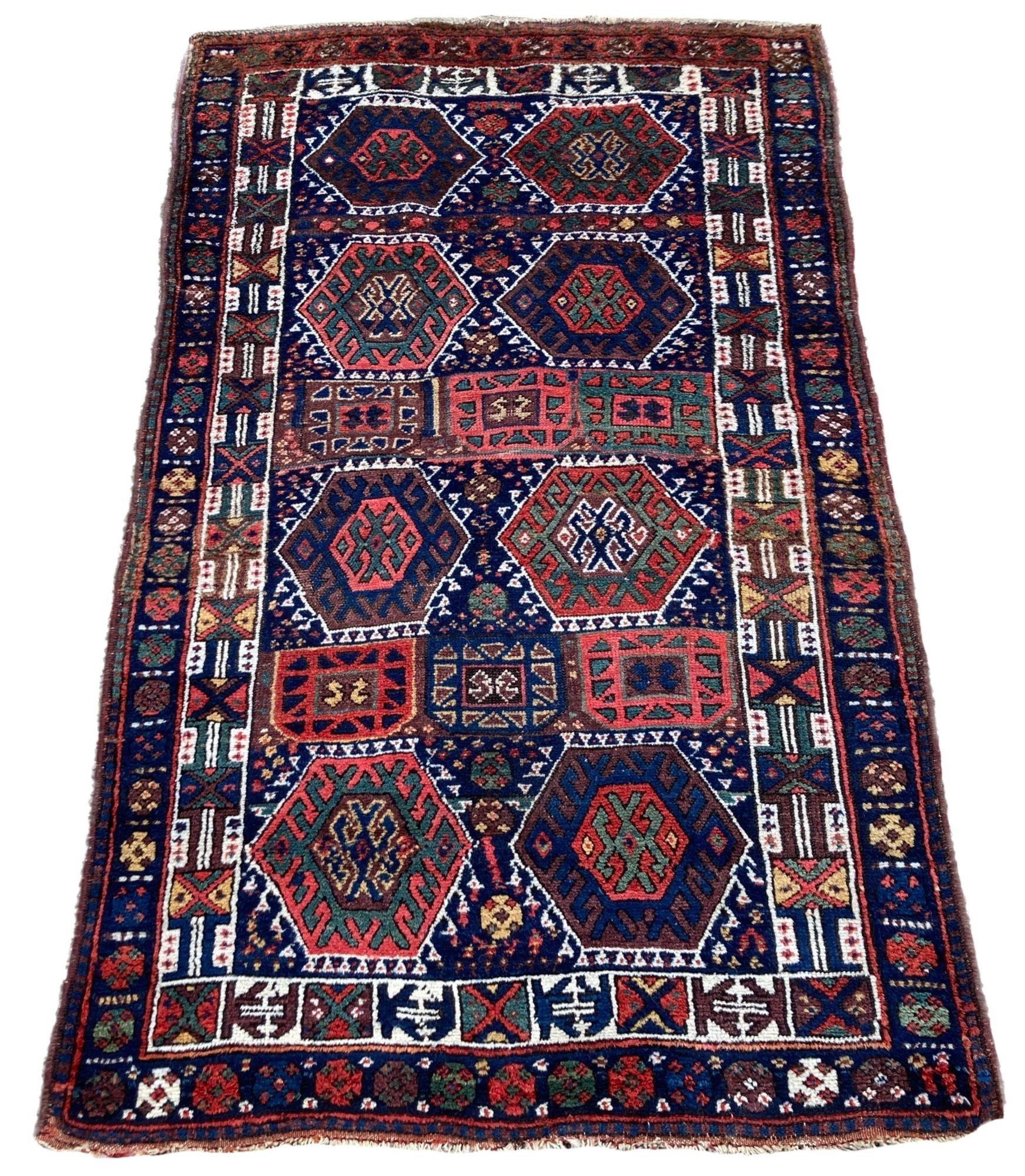 Ein wunderschöner antiker kurdischer Teppich, handgewebt um 1900. Der Teppich zeichnet sich durch ein geometrisches All-Over-Muster auf einem Feld in tiefem Indigo und einer elfenbeinfarbenen Bordüre aus. Gewebt aus weicher, samtiger Wolle und
