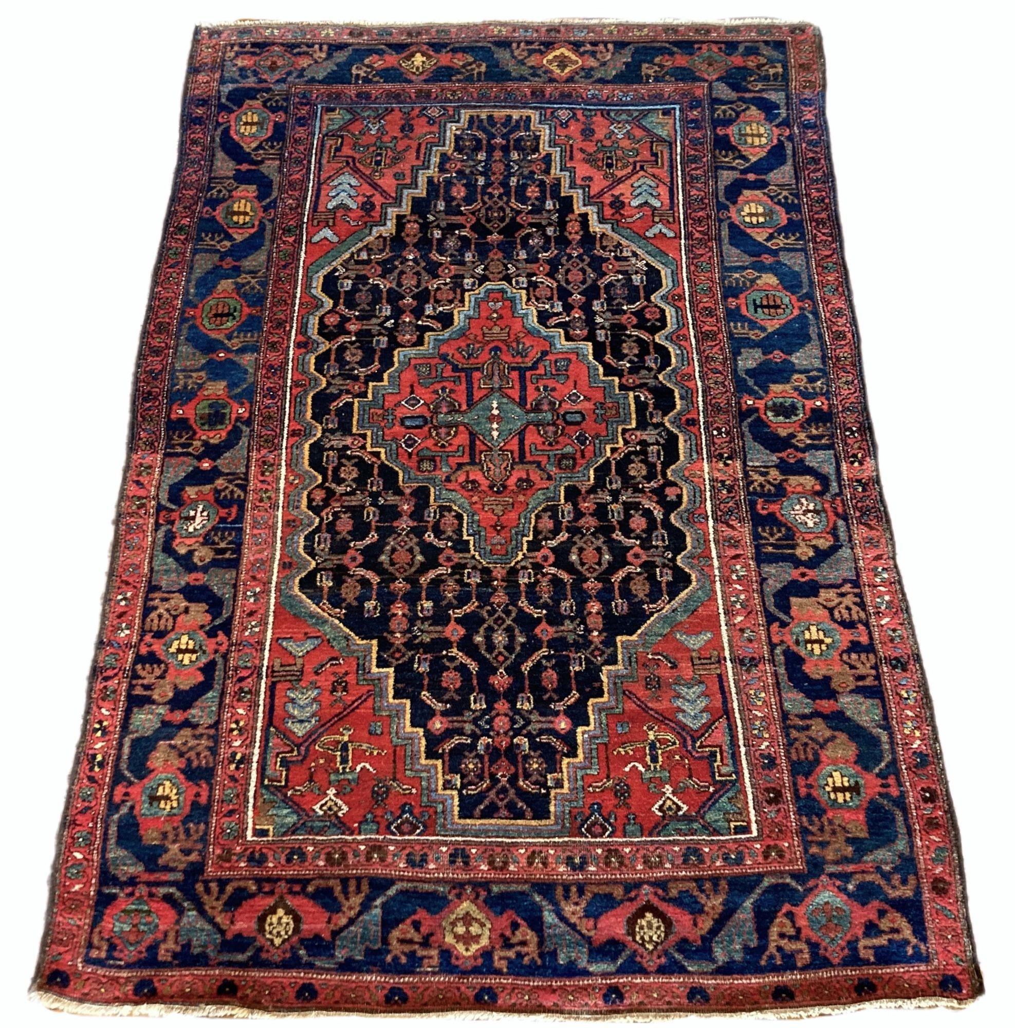 A beautiful antique Kurdish rug, handwoven circa 1910. The design features a single terracotta medallion on a deep indigo field and similar border. As with many Kurdish rugs, the dyes are particularly good and include a lovely gold and sky blue.