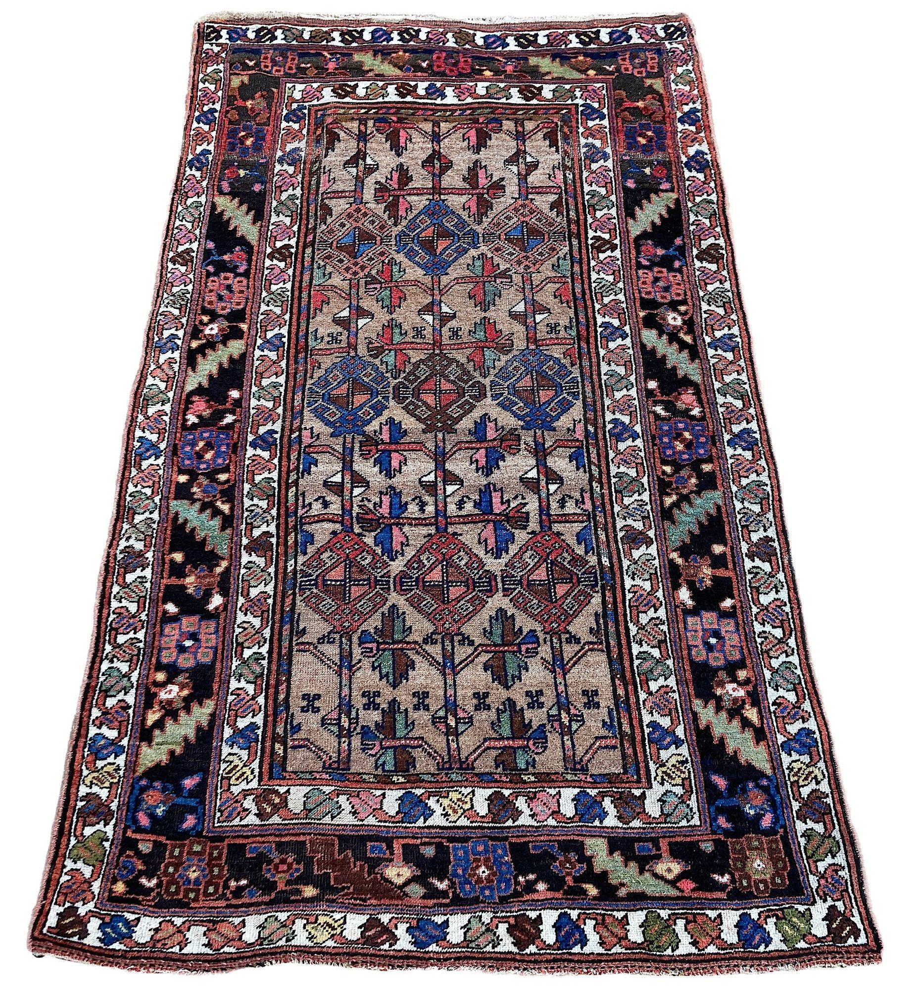 Maravillosa alfombra antigua, tejida a mano por nómadas kurdos hacia 1900. La alfombra presenta un diseño geométrico integral sobre un inusual campo camel y un borde de color añil intenso. Hermosos colores secundarios de verdes, rosas y azules, y un
