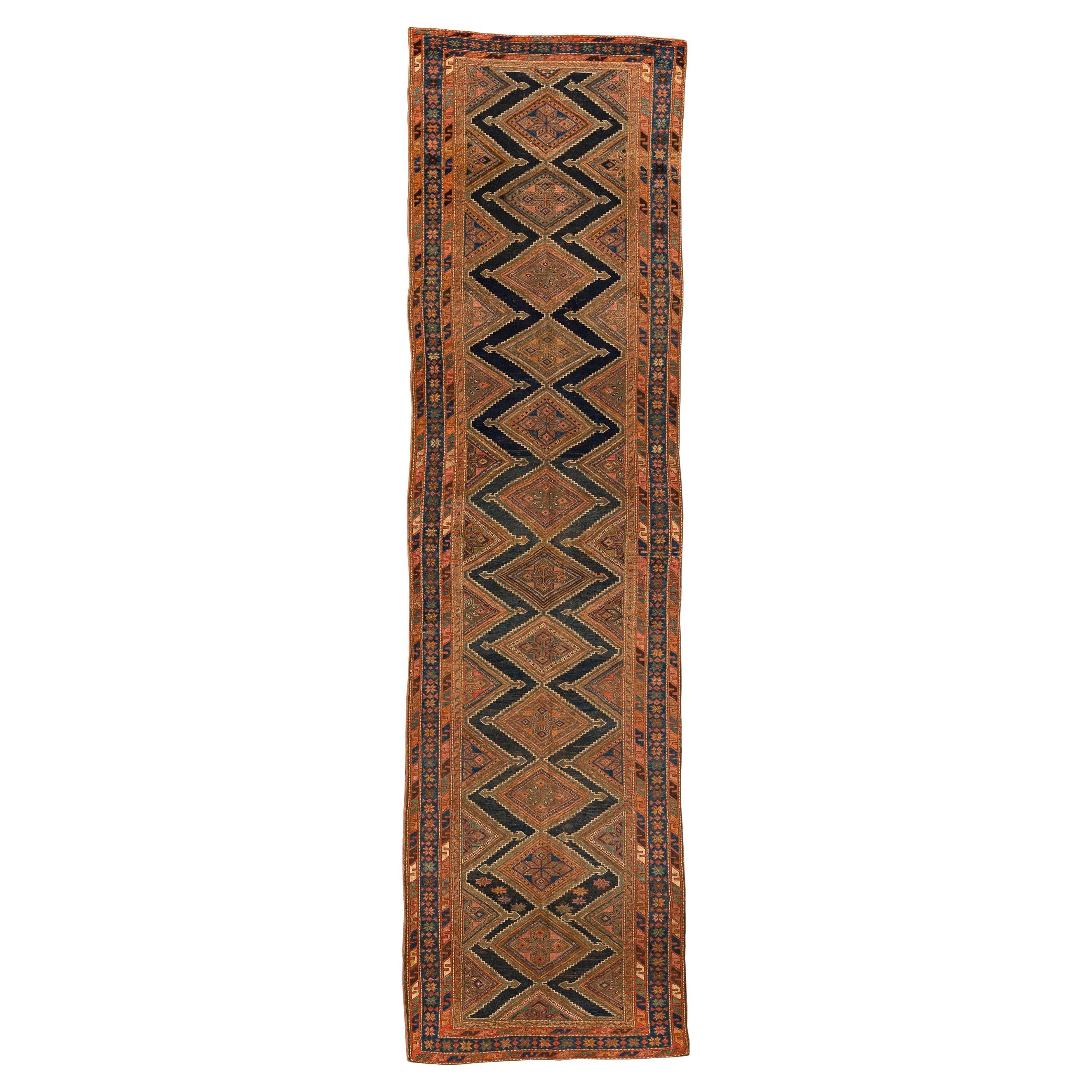 Kurdish – Northwest Persia

Twelve lozenge-shaped medallions with serrated borders and arrowheads are aligned over an abrashed navy blue field. The medallions are incomplete at the bottom and top of the rug, interrupted by the borders, giving a