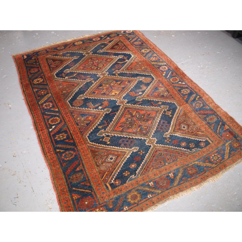 Antique Kurdish rug with interesting linked medallion design.

The rug has three linked medallions which appear to be surrounded by water courses with lily flowers and fish in the water. The border is in the same indigo blue with a large scale