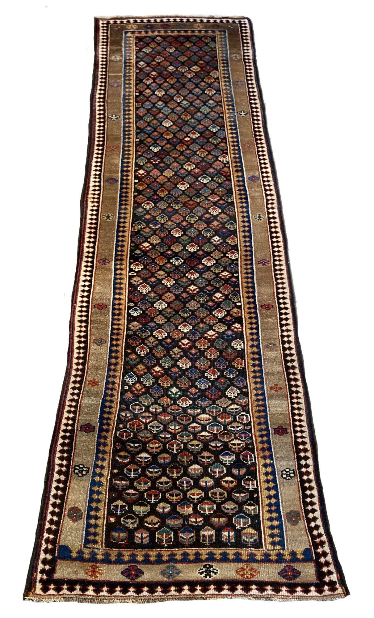Un favoloso runner curdo antico, tessuto a mano nel 1900 circa. Il design presenta un disegno geometrico all over su un campo di cioccolato intenso racchiuso da un semplice bordo color cammello. La qualità della lana è ottima e i colori secondari