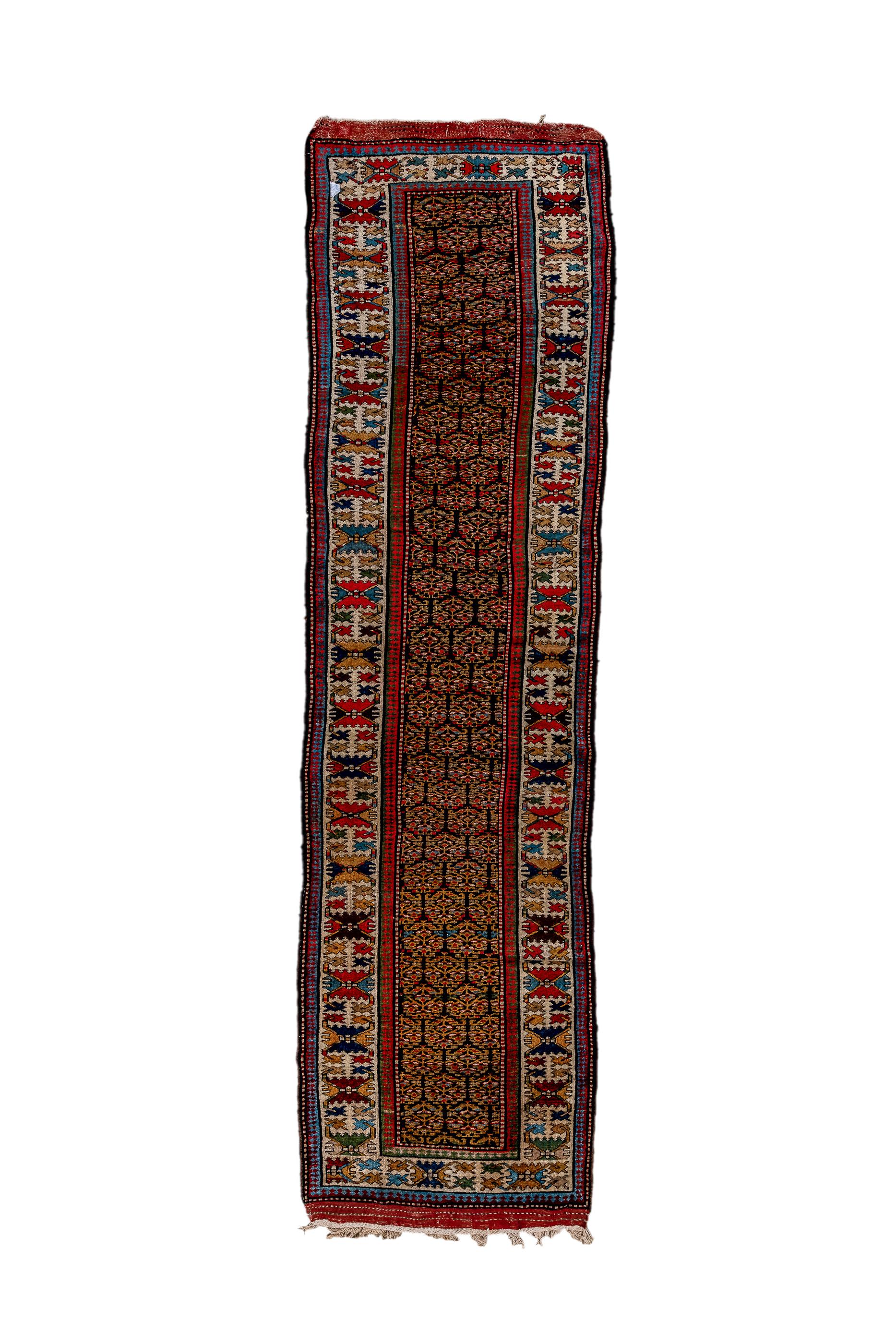 This Kurdish west Persian village runner shows a dark brown field covered with half drop rows of stylized, openwork flowers in the characteristic Kurdish style. The ecru  main border exhibits a version of the “crab” pattern with red or goldenrod
