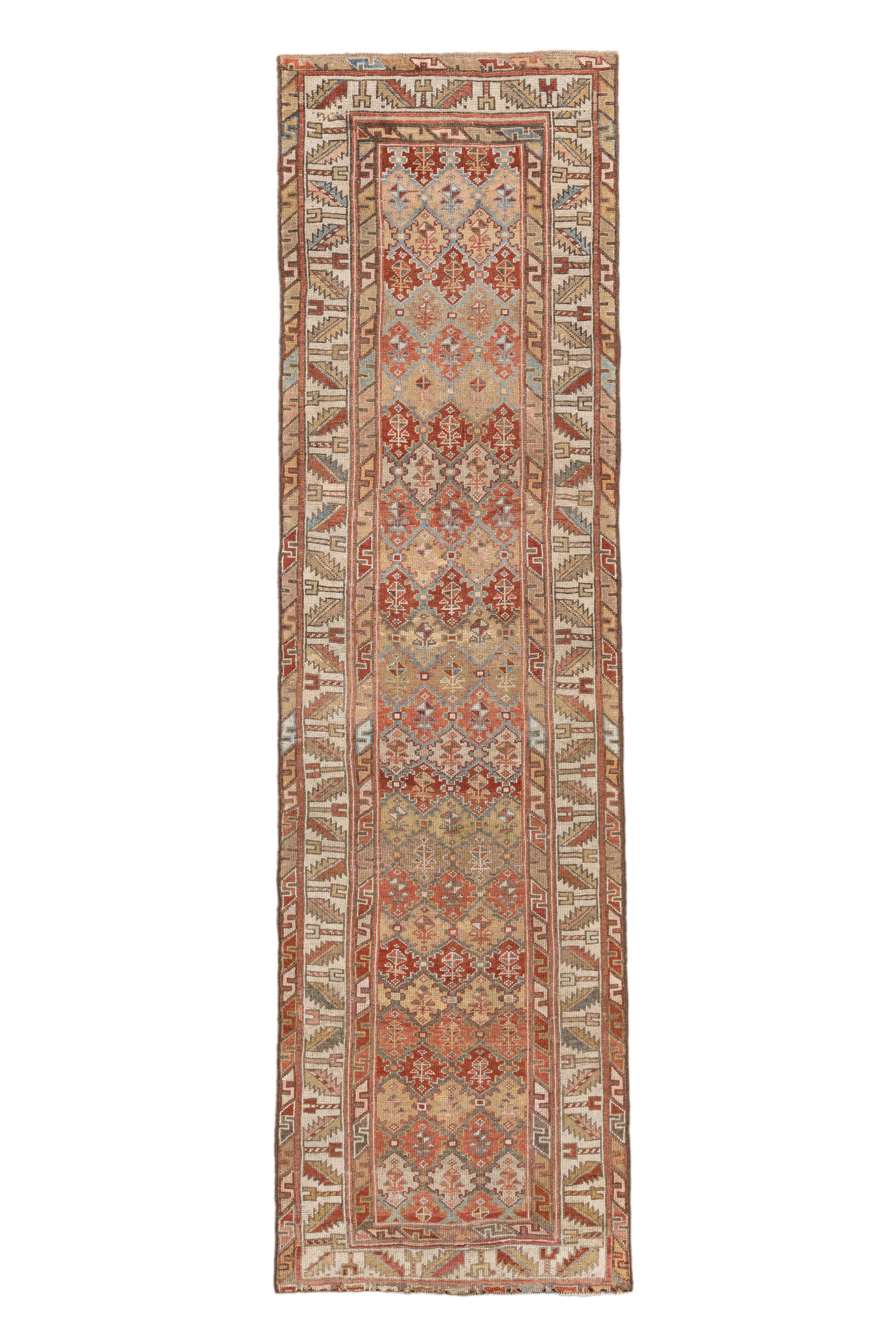  Esta antigua alfombra kurda, tejida a principios del siglo XX, muestra una dinámica serie de medallones dentados y estilizados motivos florales en una paleta de colores bellamente envejecida de rojo óxido, camel, azul cielo y oliva. El borde