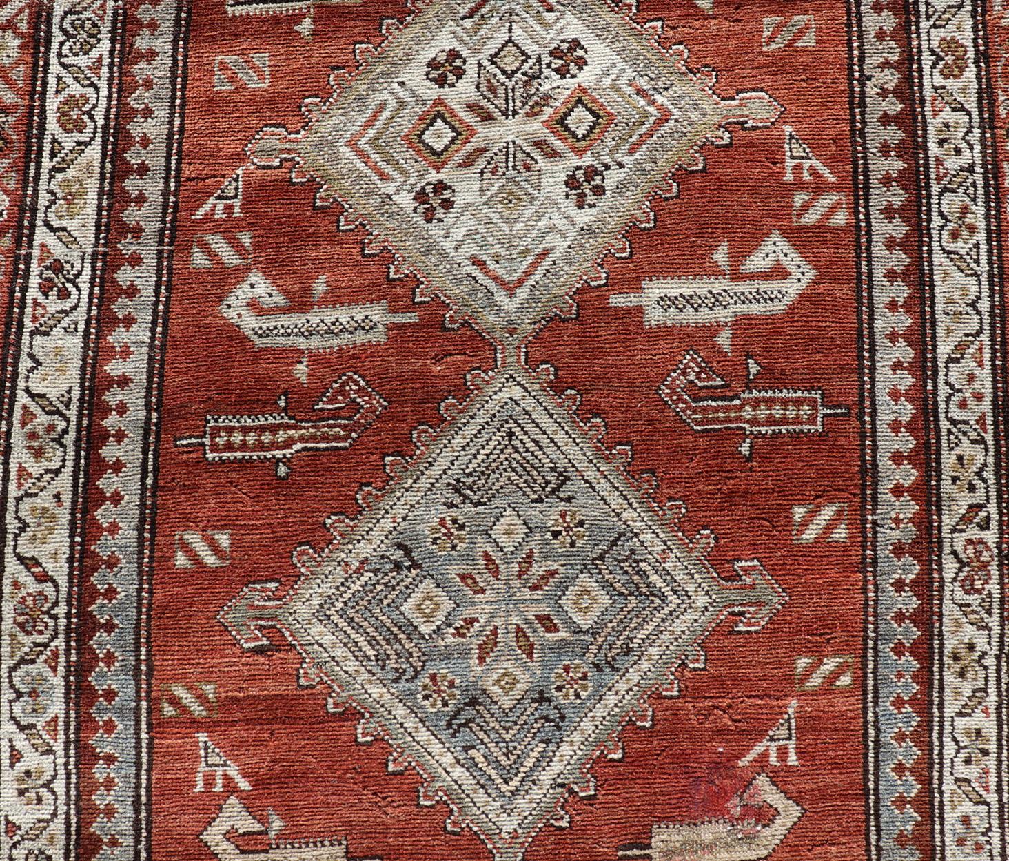 Wool Antique Kurdish Runner with Rusty Red Background and Medallions Tribal Motifs For Sale