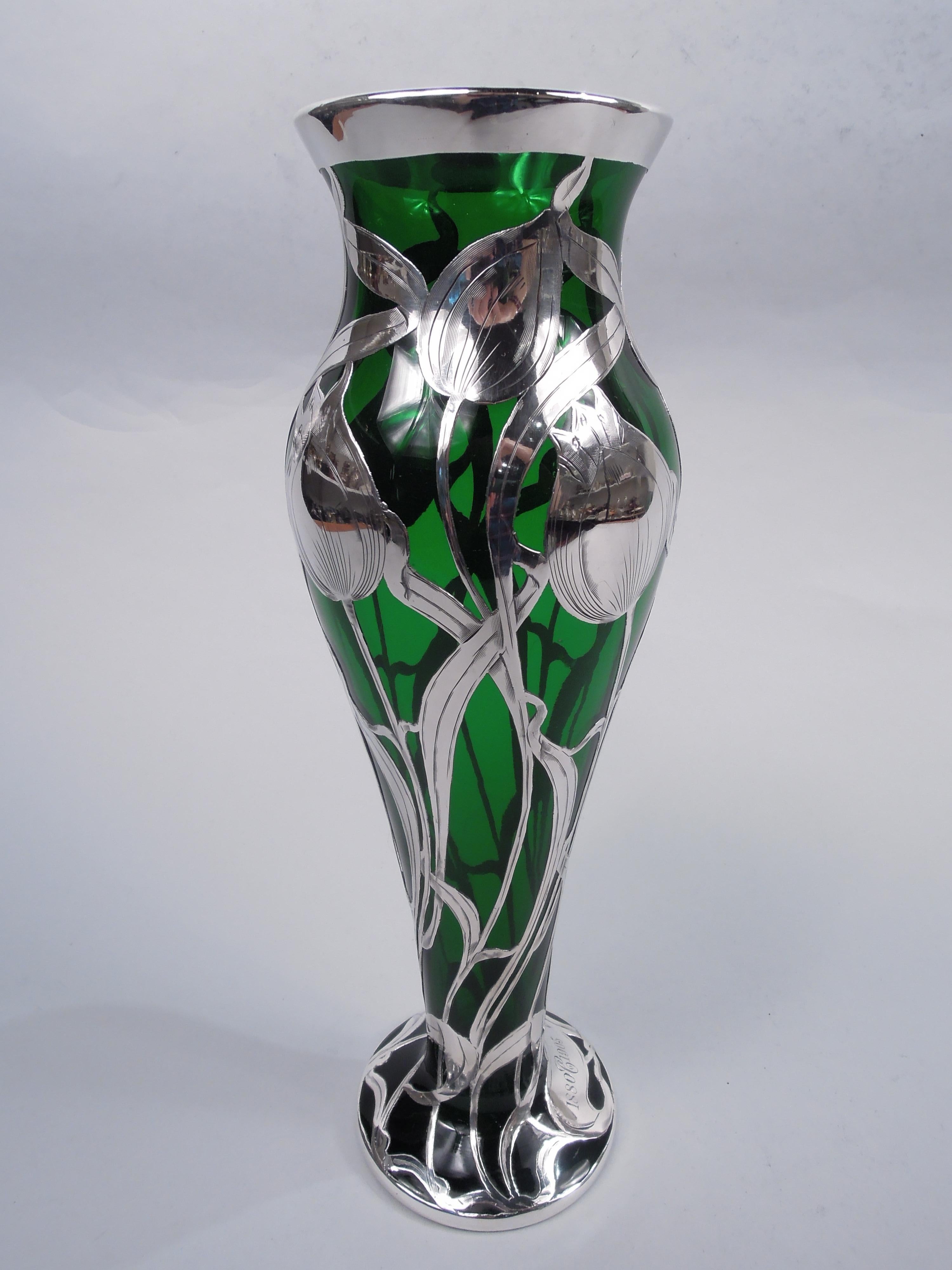 Turn-of-the-century Art Nouveau glass vase with engraved silver overlay. Elongated baluster with flared rim and raised foot. Overlay in form of budding and blooming tulips with entwined and whiplash tendrils. On foot is scrolled cartouche engraved
