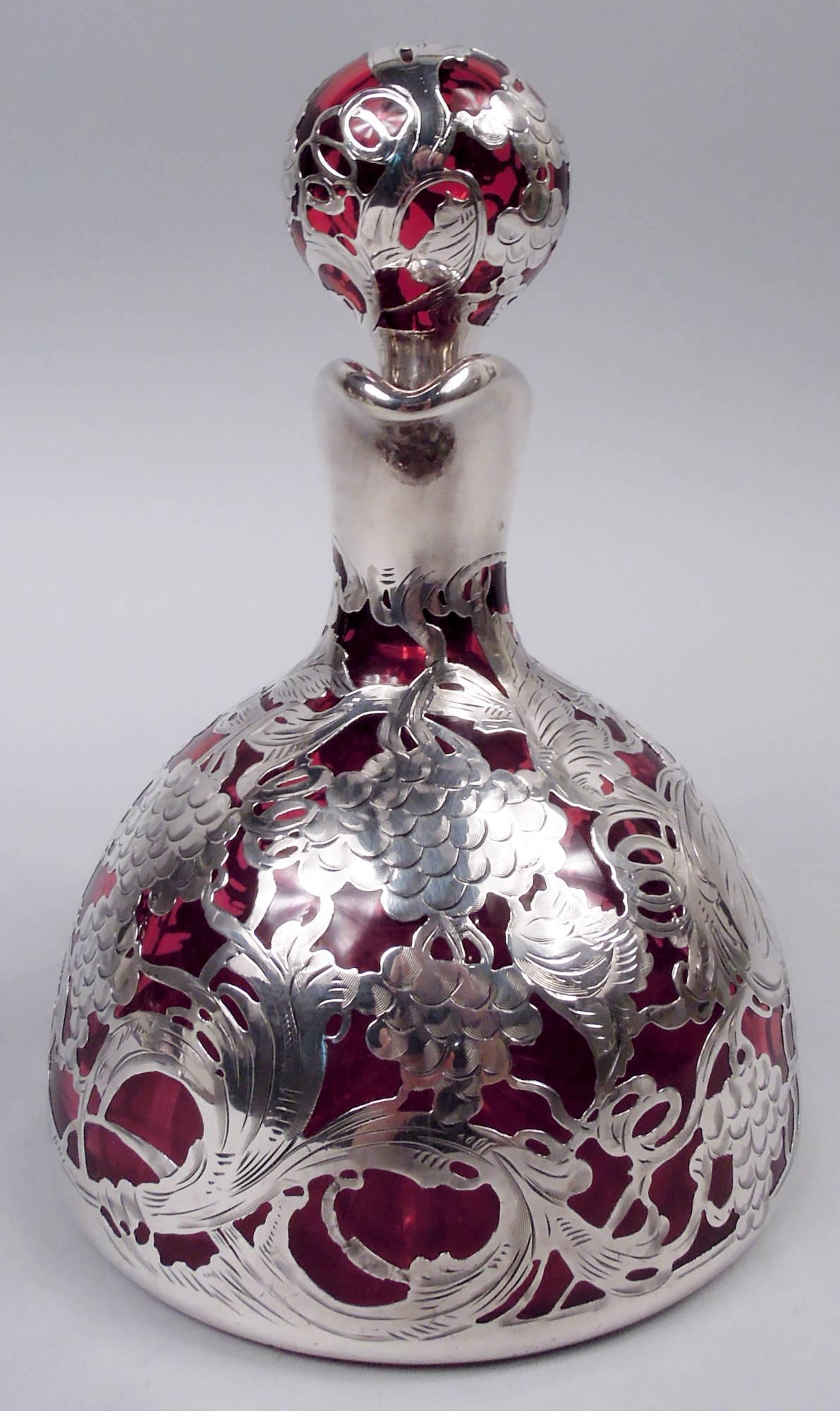 Art Nouveau glass decanter with engraved silver overlay, ca 1900. Hemispheric bowl with star cut to underside. Short neck and helmet mouth in silver collar as is high-looping c-scroll handle. Ball stopper. Dense overlay in form of fruiting grapevine