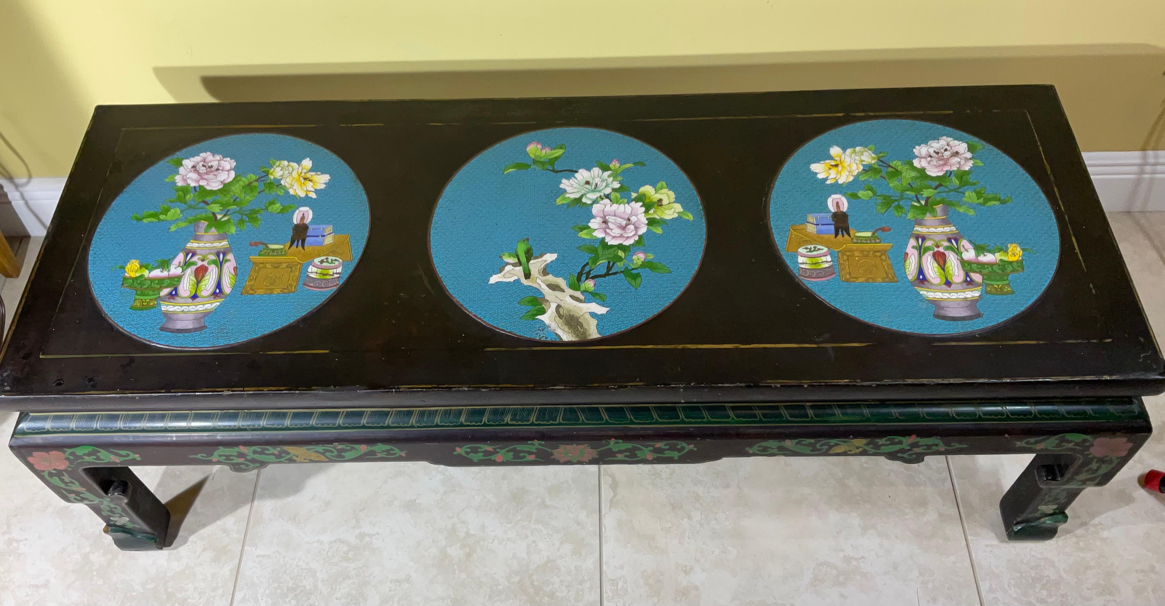 A black lacquer Chinese coffee table with three large cloisonné turquoise circles on top , depicting flowers birds and garden decor  , The four sides of the table are nicely hand painted , and the table is very solid standing on the floor and ready