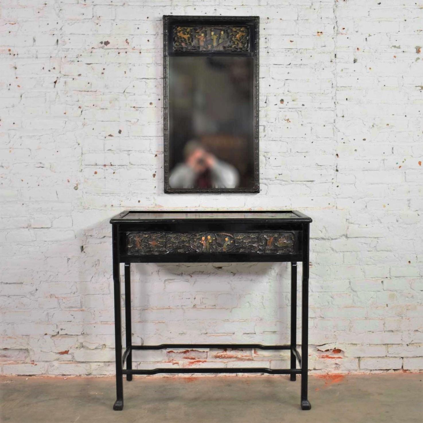 Handsome antique Asian black lacquered console table and matching mirror with exceptional deep hand carved lacquer details of Asian figures and florals. Some painted colors and some black. Both are in wonderful antique condition. There are small