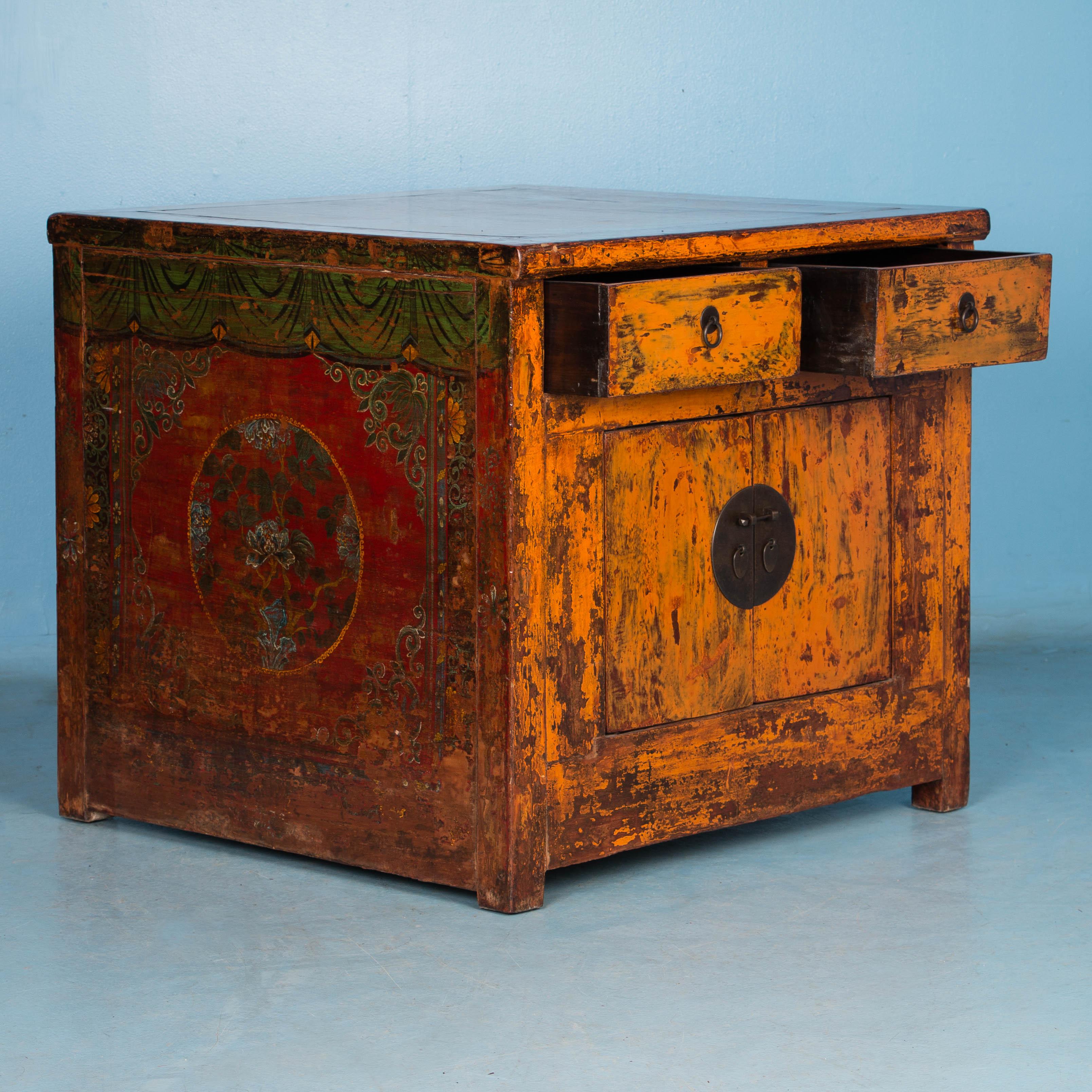 This stunning square lacquered Chinese cabinet still maintains the vibrant original paint with dominant colors of orange, red and green. Through years of use, many areas of paint have been worn down to reveal darker shades of natural wood below