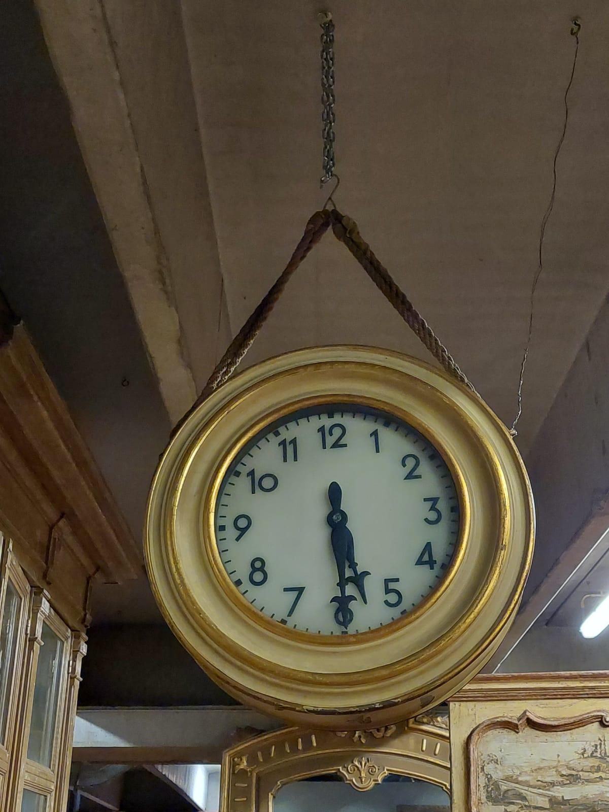 Antique train station clock, round in shape, hand-lacquered with yellow and gilding, the time can be read from both sides, double-faced, carved hands, very nice, it was hung with the original rope. Built in the 19th century for a station in northern