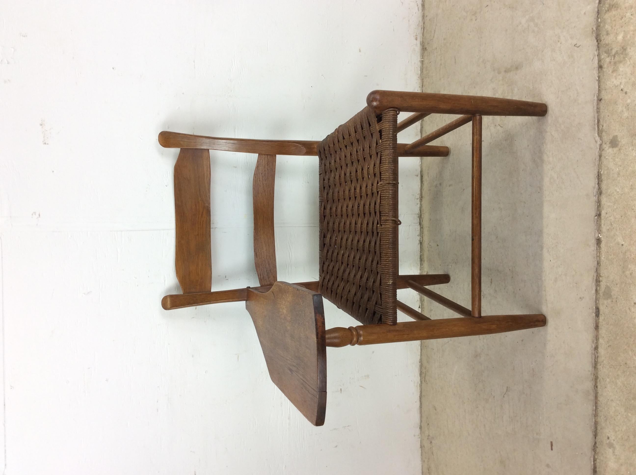 Cette chaise d'écriture antique est construite en bois dur, avec une finition originale en chêne foncé, un siège à dossier en échelle avec une assise en jonc vintage, et une surface d'écriture en chêne massif.

Dimensions : 26w 27d 33.25h 18sh