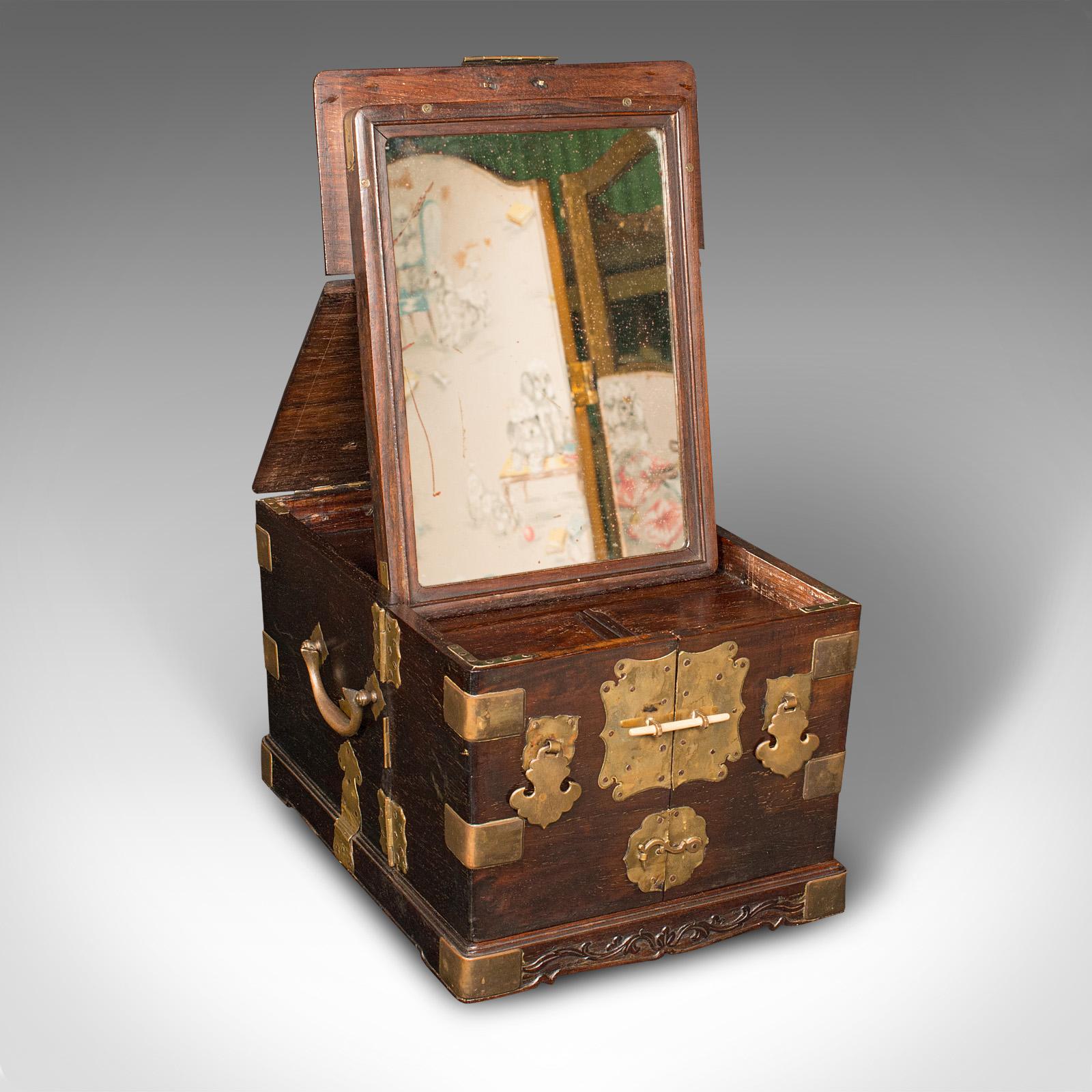
This is an antique ladies travelling vanity box. A Chinese, elm and brass dressing table case with internal mirror, dating to the early 20th century, circa 1920.

Fascinating set of openings and storage, with a distinctive appearance
Displays a
