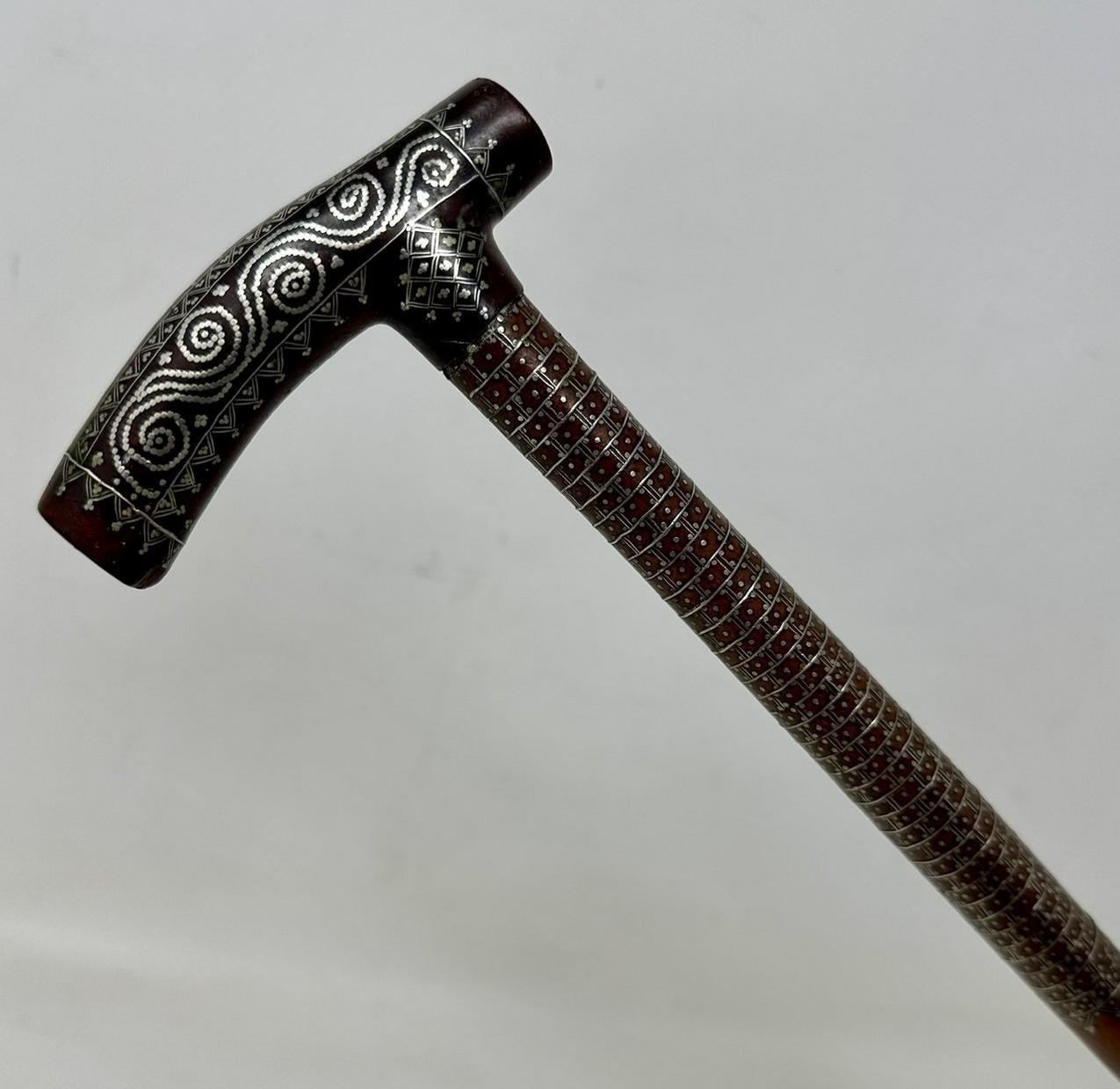 Fine quality and quite rare Ladys Sterling Silver inlaid dark Malacca Walking Stick of neat proportions, made during the last half of the Nineteenth Century.  

The Tau shaped handle with unusual silver claute pique inlaid decoration depicting
