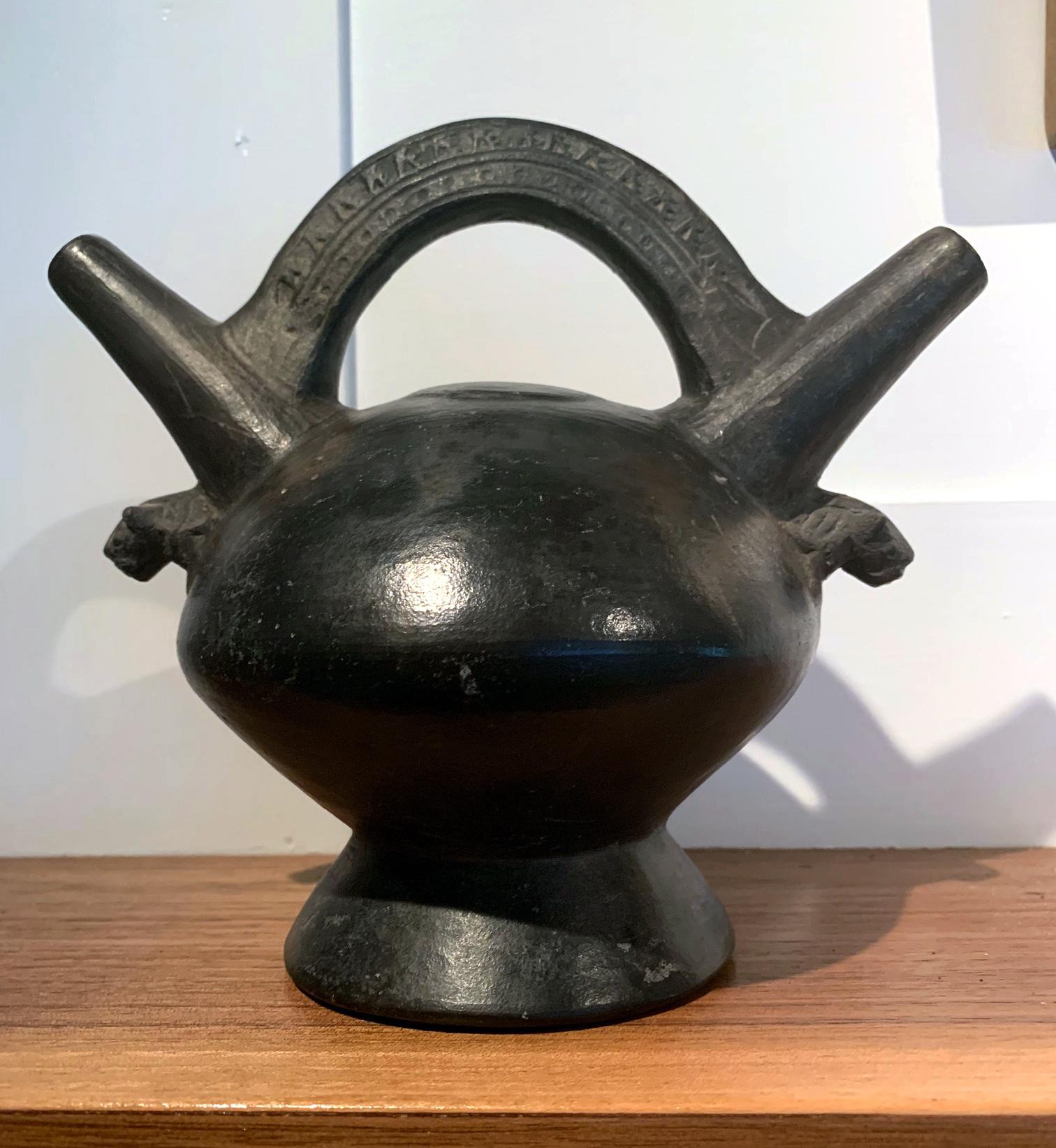 A polished black double spouted vessel from the Pre-Columbian Lambayeque culture (also known as Sicán 750AD -1375 AD) on the northern coast of Peru, straddling the Middle Horizon and Late Intermediate Period of the ancient Central Andes and often