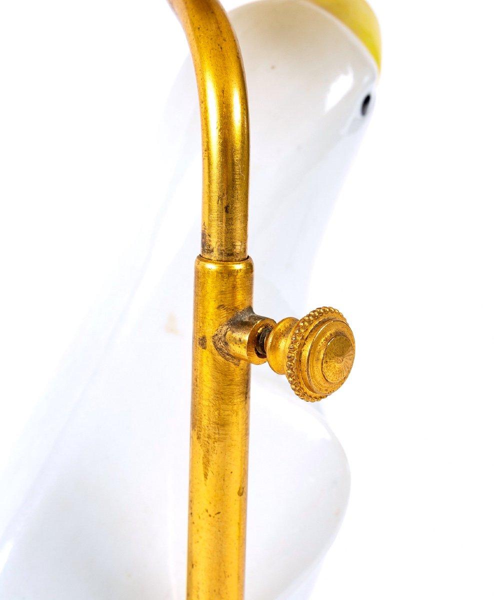 Ravissante petite lampe ancienne, montage soigné et original, en très belle porcelaine de Chine, émail blanc et jaune, représentant une perruche aux ailes repliées, au regard serein perchée sur une base rocailleuse ajourée.

Le cadre en laiton