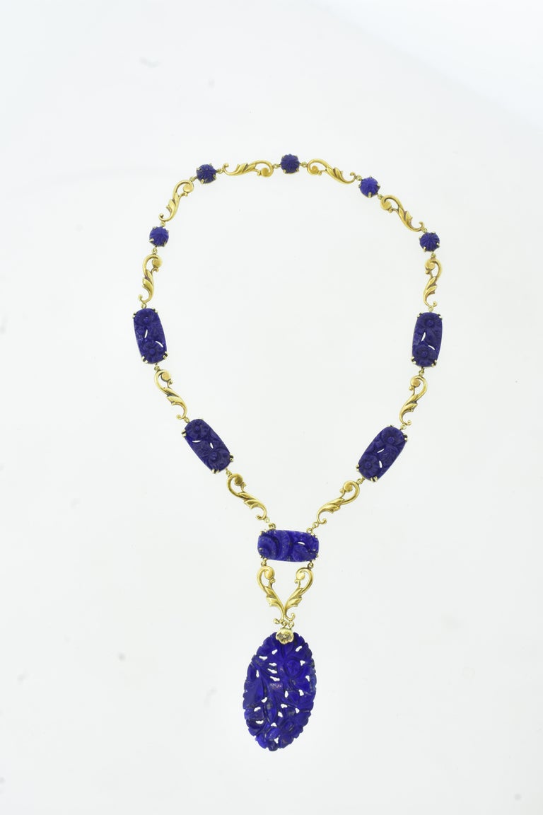 Antique necklace of finely carved and natural vivid blue lapis.  This handmade gold necklace is in total 17 inches long.  The pendant portion is 3 inches in length, and the necklace of punctuated early gold period scrolls and fine lapis is
14