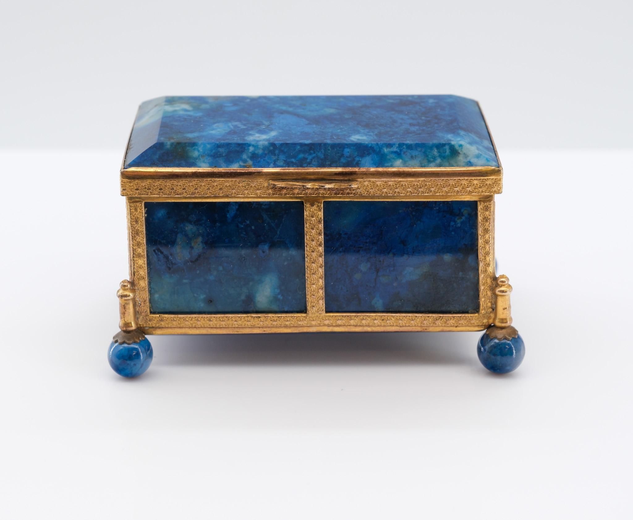Precioso cofre antiguo en miniatura de lapislázuli y metal dorado, asentado sobre cuatro pies de bola. Manera de Palais Royal. Francés, hacia 1880.

El lapislázuli semiprecioso muestra un color y una composición maravillosos de azul intenso.
  
El