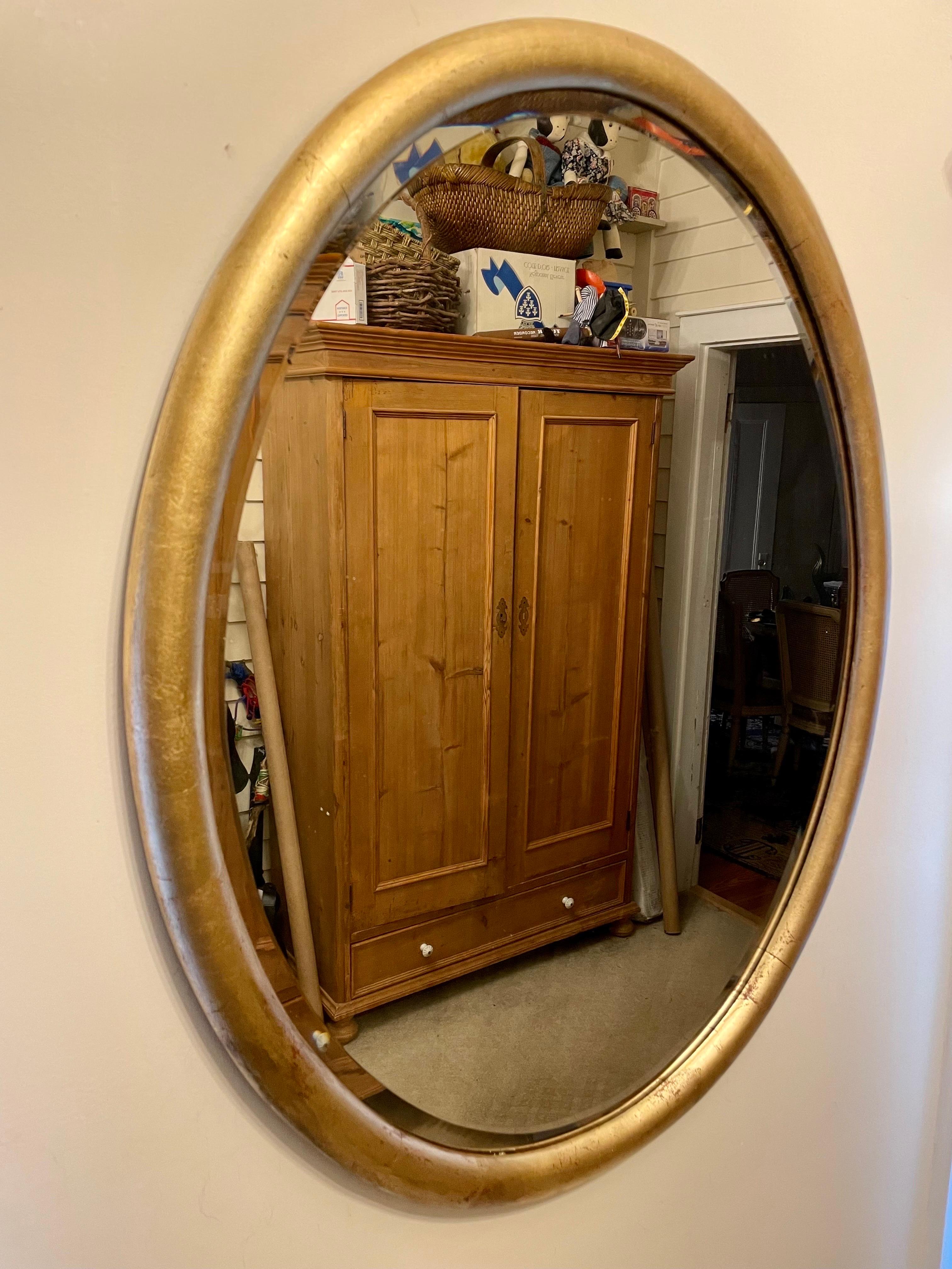 Antique gilt wood oval mirror. Original beveled mirror has great distressing and age marks from years of use. Great size, Measures 30