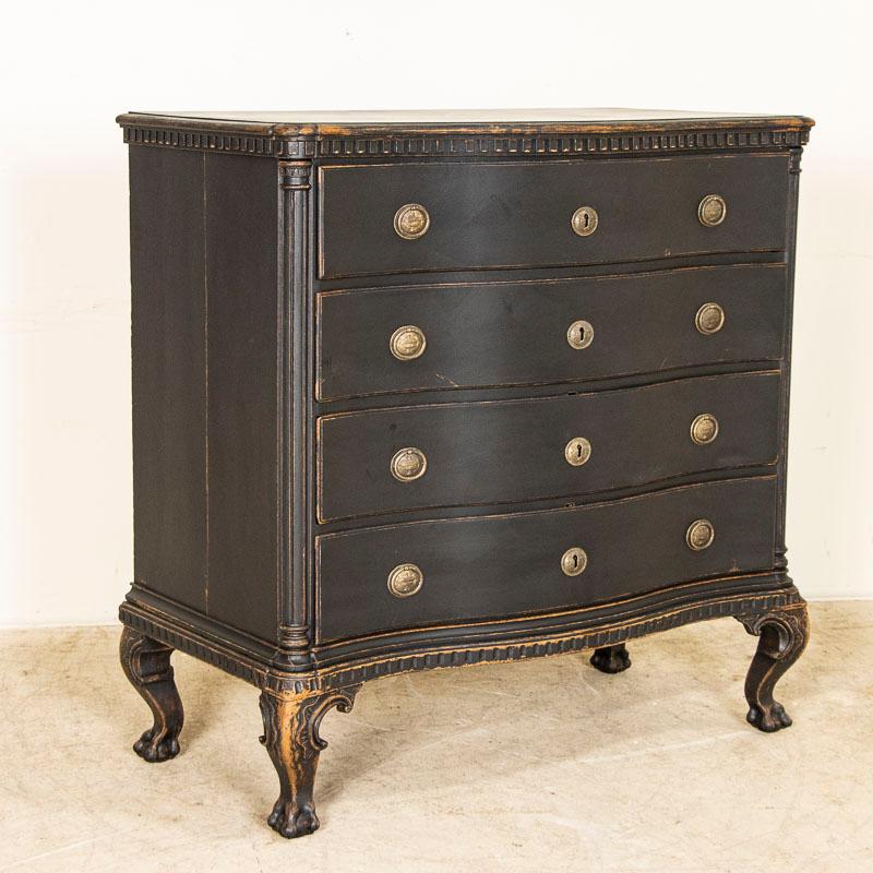 This antique rococo chest of drawers from Denmark features a serpentine front, brass hardware pulls and an exceptional (newer) matte black painted finish. The lightly scraped off/distressed black paint creates a warm contrast with the natural oak