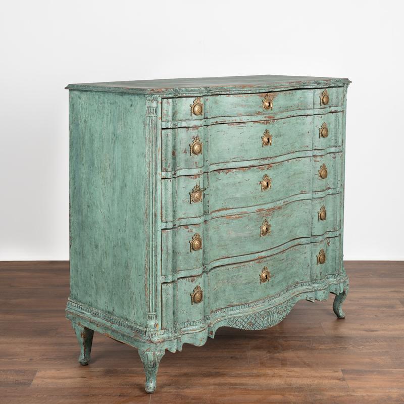 It is the striking blue painted finish that draws one to this handsome large oak chest of drawers. Later professionally painted in blue and teal shades, the finish has been lightly scraped and sanded exposing the natural wood beneath and beautifully