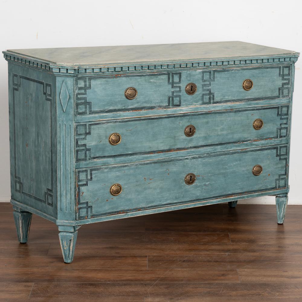 A large decorative Gustavian style pine chest of drawers painted in blue shades.
Contrasting faux marble painted top and dentil moldings.
Three drawers decorated with painted 