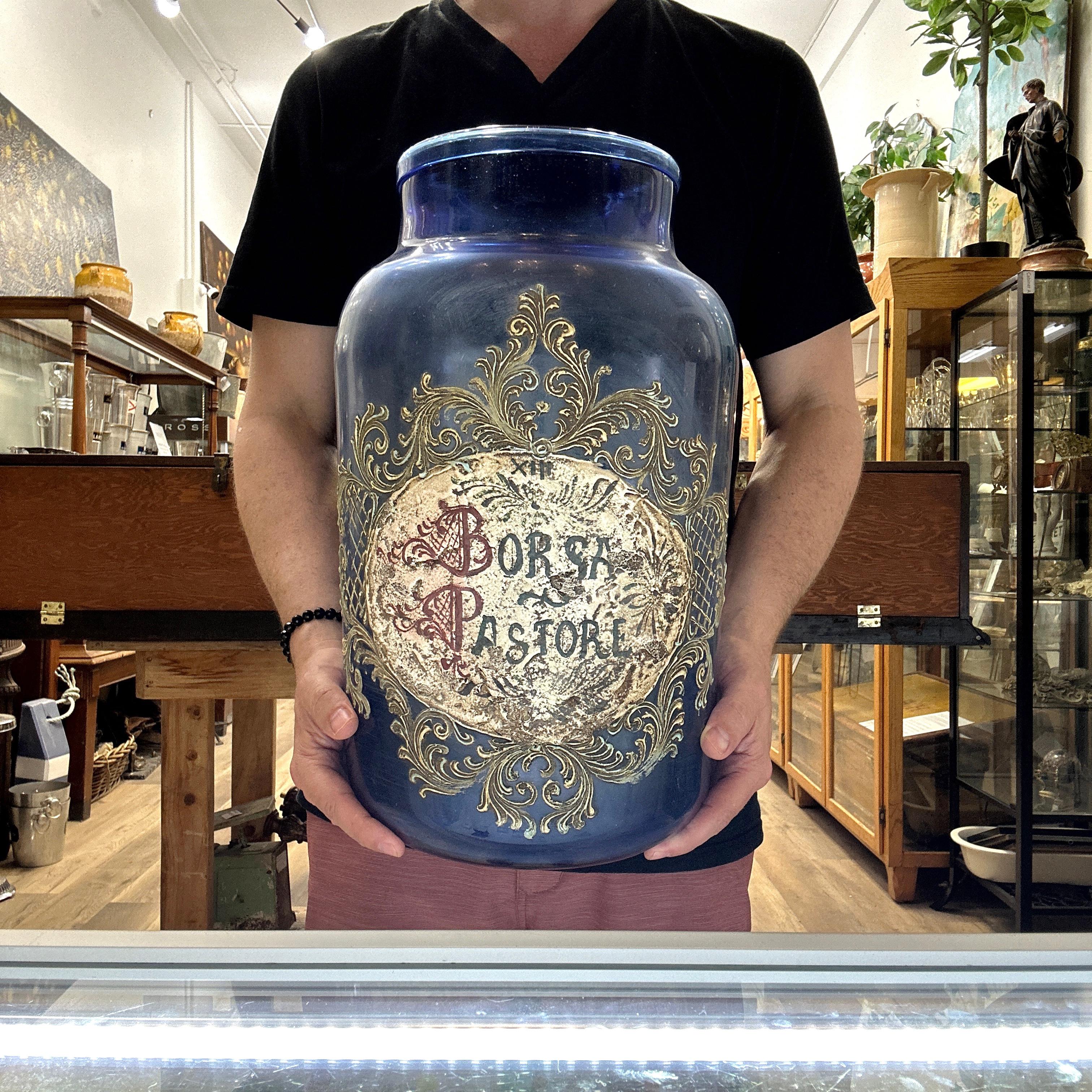 Here is a beautiful Antique and Large Italian Murano Glass Pharmacy Apothecary Jar. Elaborately hand painted and gilt on a blue tinted Murano glass. Reads “BORSA PASTORE” on the label which refers to Capsella bursa-pastoris, commonly known as