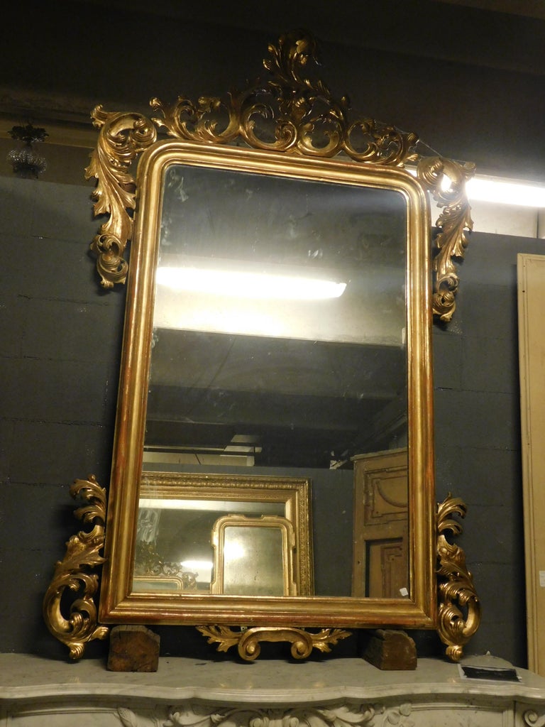 Ancient large hand carved wooden mirror, with antique leaf gilding, from the end of the 18th century, from a castle in France.
It was initially used over an important fireplace, it can be seen from the great refinement of the vegetable sculptures,