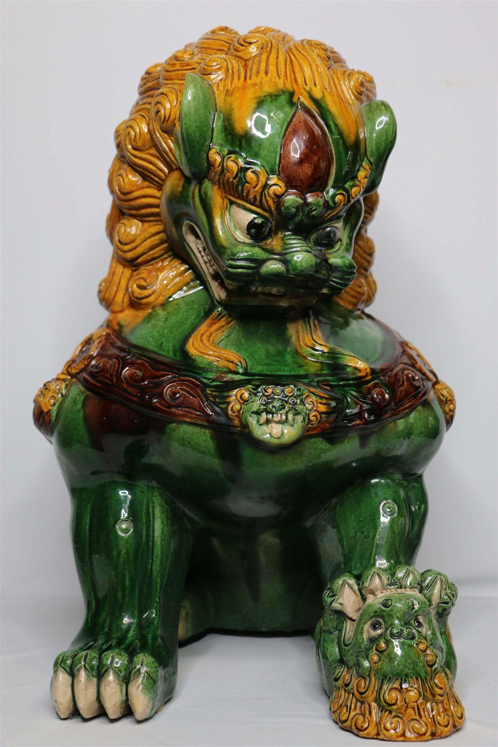 Large Chinese Foo lion. Predominantly green glaze with golden yellow detail attributed to Tang Dynasty glaze coloring. This unusually large foo dog displays fierce countenances. It hold the traditional 'ball'. Typically seen as part of a pair