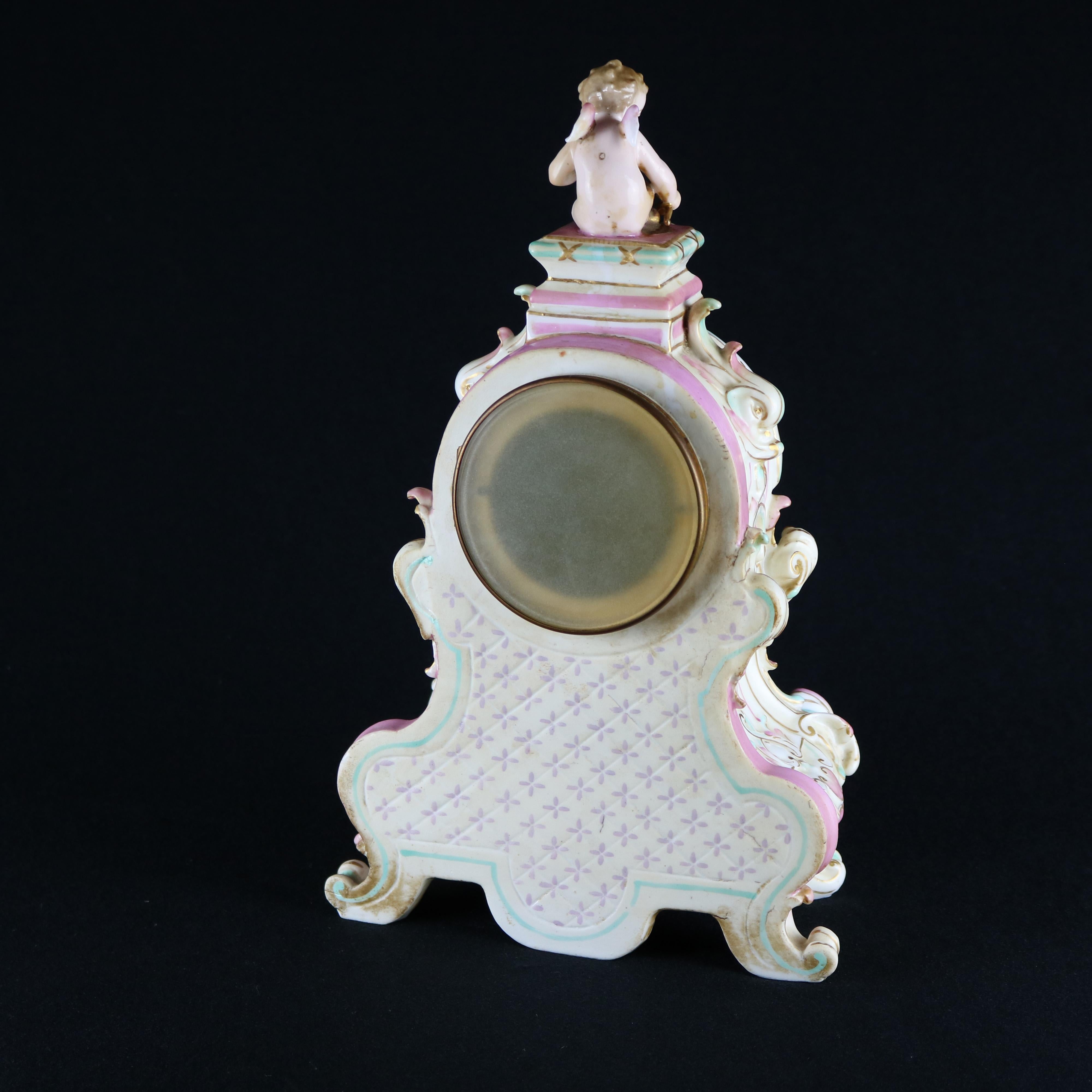 An antique and large figural German clock in the manner of Meissen offers cupid finial surmounting hand painted and gilt scroll and foliate decorated porcelain case obverse having Classical cherub scene and floral reserve, raised on scroll form feet