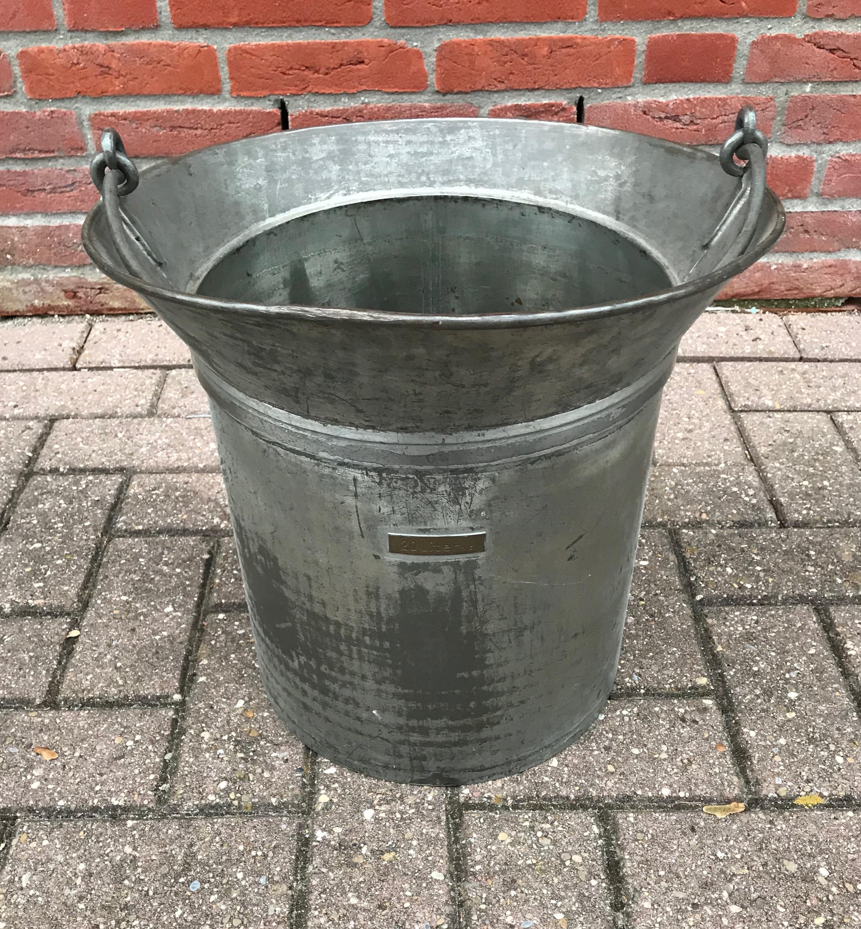 Stylish and decorative, early 1900s calibration bucket.

The wonderful shape and the Industrial color makes this hand-hammered wrought iron bucket with rivets highly attractive and decorative. Because of its great look, size, strength and durability