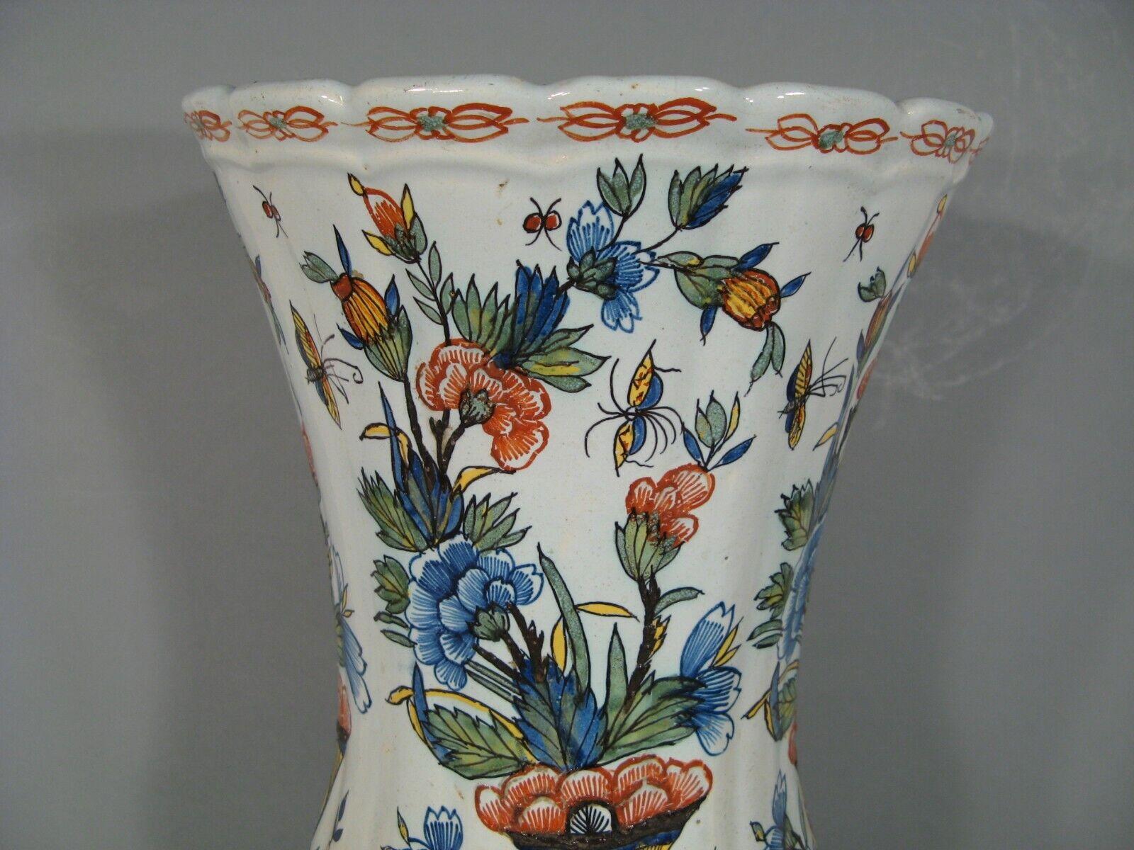 This impressive large faience vase, attributed to the Desvres Fourmaintraux-Courquin manufactory, features a vibrant polychrome decoration with motifs of cornucopias, butterflies, and floral elements. The vase dates back to the second half of the