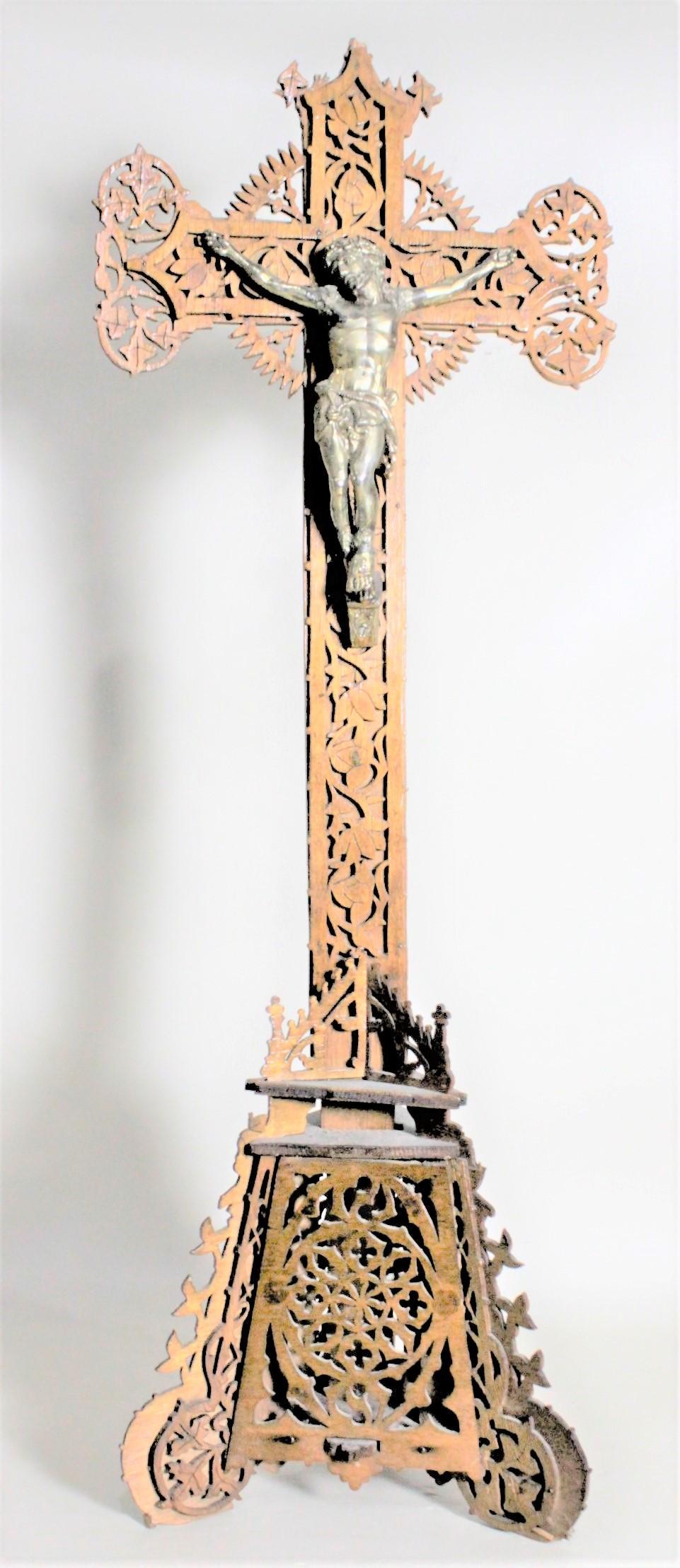 This extremely detailed and ornately handcrafted wooden Folk Art Crucifix is unsigned, but presumed to have been made in Eastern Europe, possibly Austria, in circa 1920. The cross and Stand are both intricately cut and carved of a softwood and a
