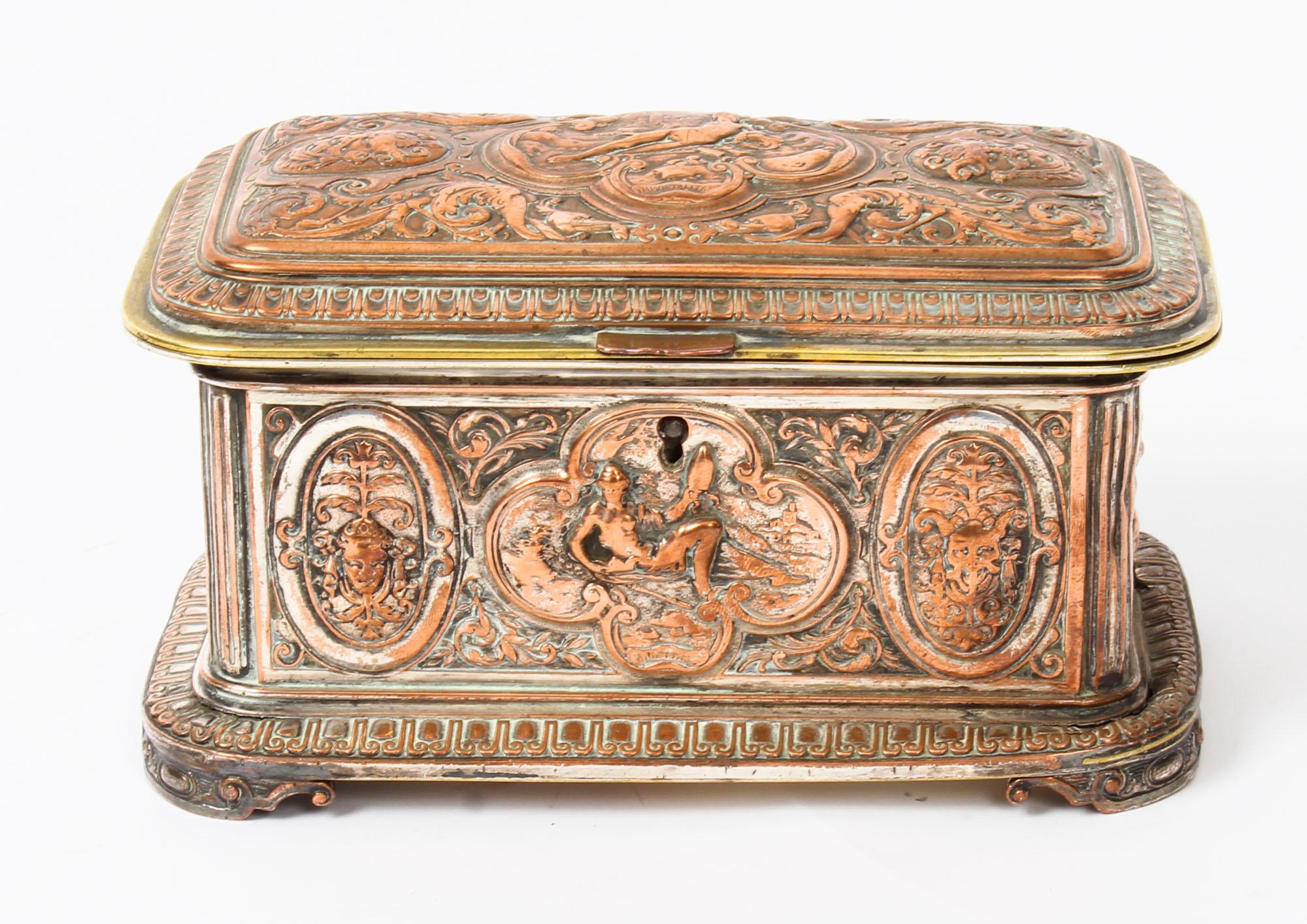 A beautiful Victorian gilt and silver plated copper jewellery casket in the manner of Elkington, date: circa 1870.
 
The rectangular casket features superb cast plaques which feature reclining nudes with masks and is raised on corner ribbon