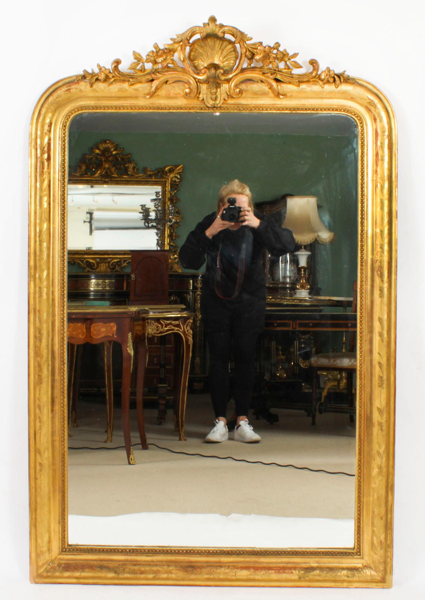 This is a large impressive antique French carved giltwood and gesso wall mirror, circa 1860 in date.
 
The frame is surmounted with a striking carved giltwood central finial with anthemion, acanthus leaf, foliage and berries decoration. The