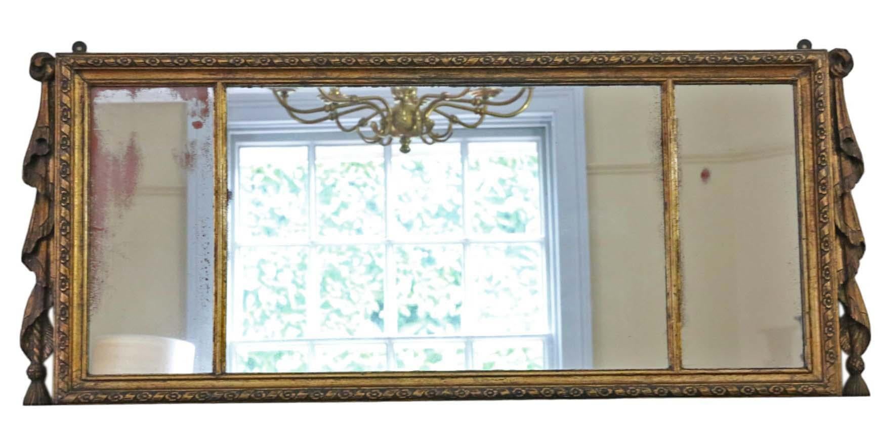 Antique large gilt overmantle wall mirror from the 19th Century, featuring a fine quality decorative swag design.

This mirror captivates with its simple yet striking design, lending character to any suitable space. The frame is solid, devoid of