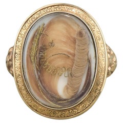Bague ancienne face à médaillon en or avec travail de cheveux, gravée en 1860