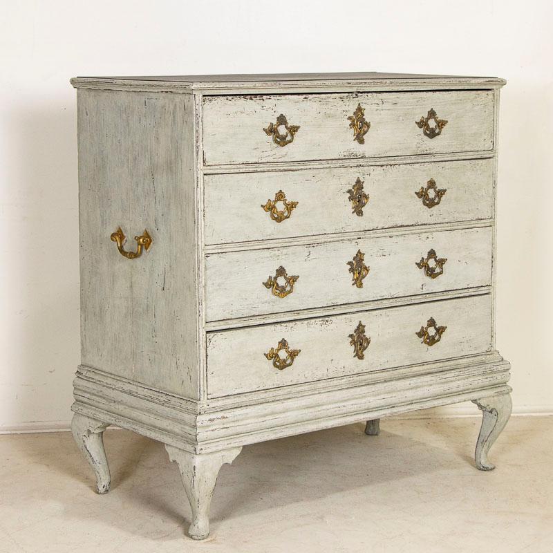 The gray painted finish creates a captivating allure in this attractive large oak chest of four drawers with brass pulls. Later professionally applied, the layers of gray (with shades of blue and white) paint compliment the age, style and graceful