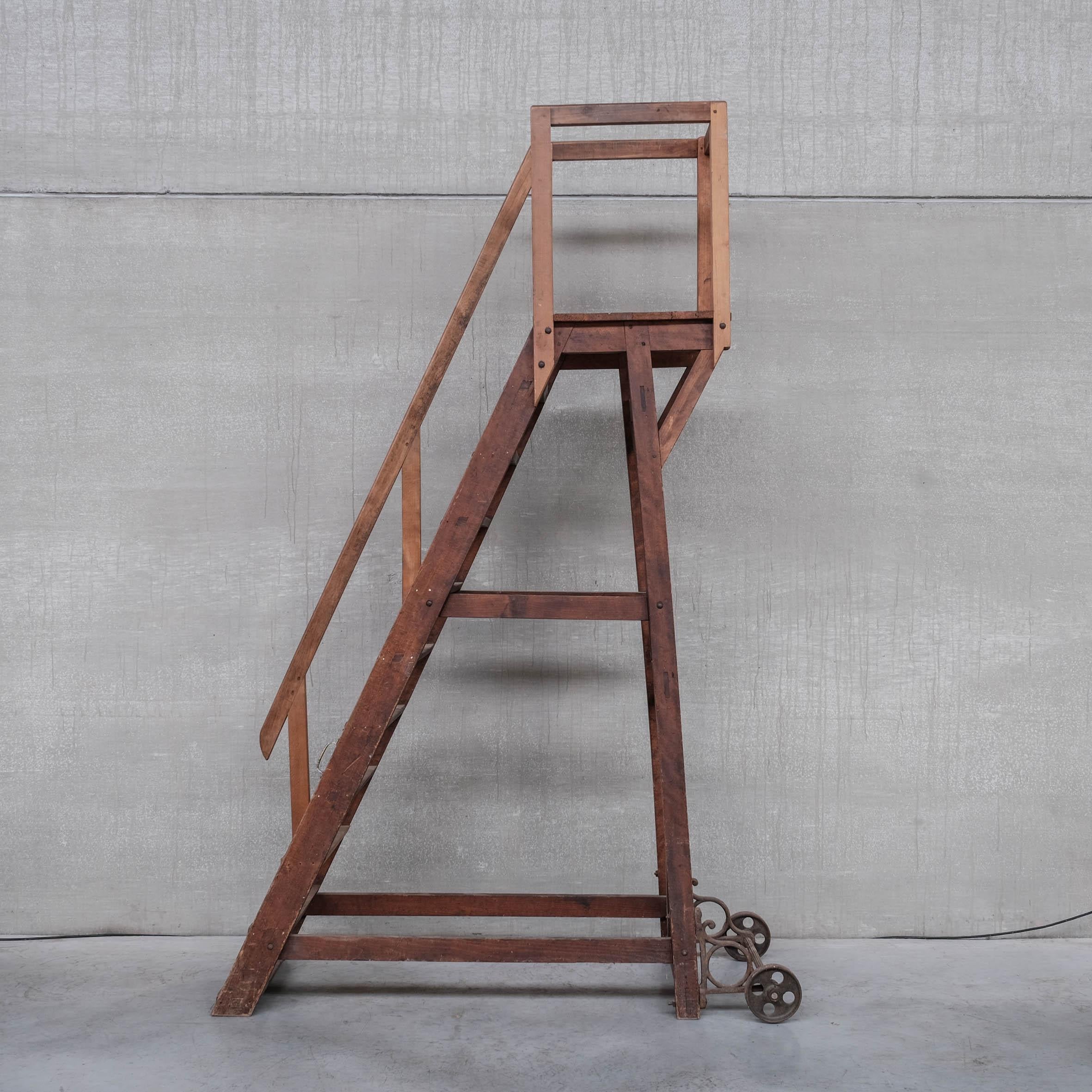 Una gran escalera móvil de tamaño normal. 

Francia, c1930s. 

Las ruedas y soportes de hierro de alta resistencia hacen que esta pieza sea funcional. 

Barandilla a un lado y pasamanos en la plataforma para mayor seguridad. 

Probablemente