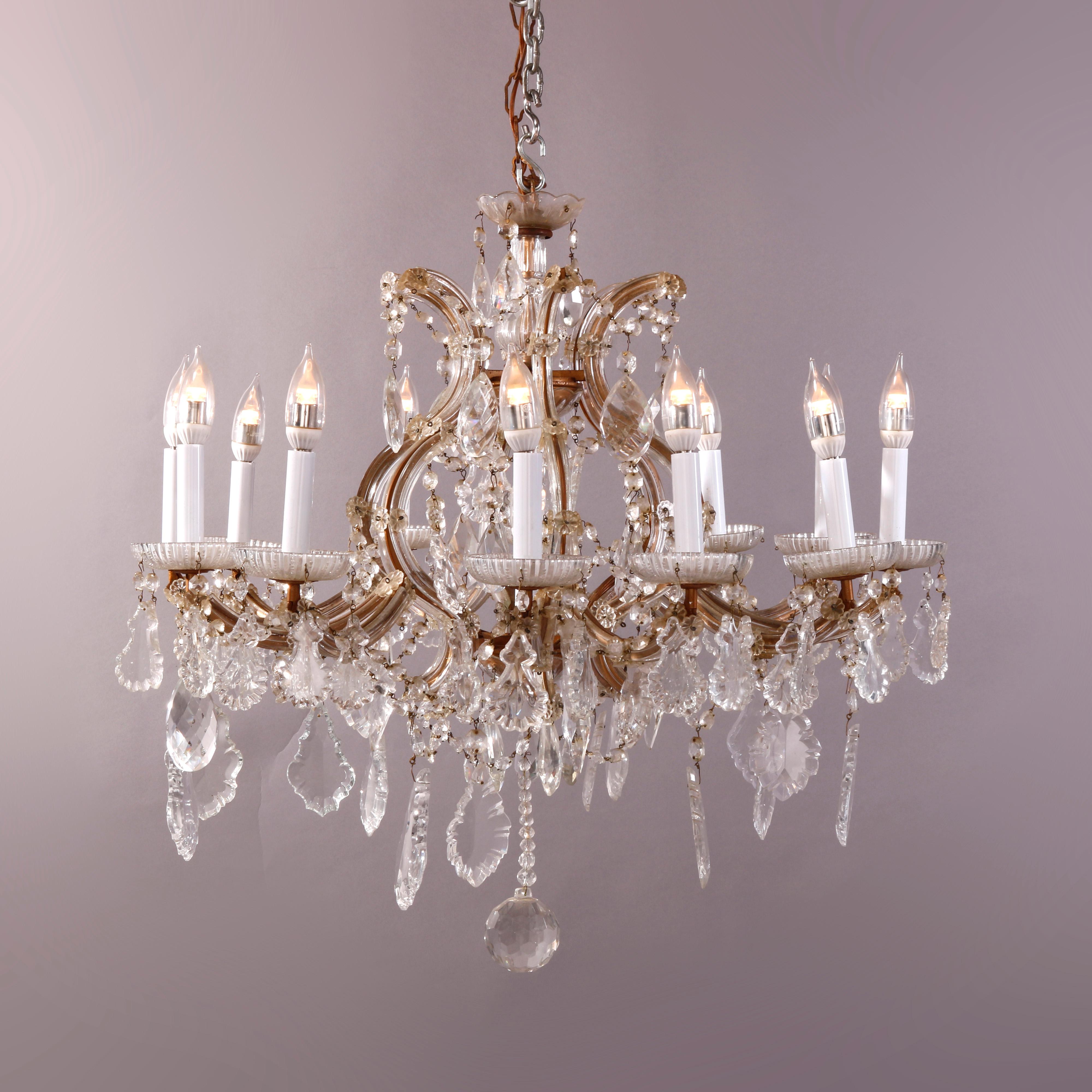 An oversized antique Italian style crystal chandelier offers brass frame with twelve scroll form arms terminating in candle lights surrounding central light and having drop and strung cut crystals throughout, c1930

Measures - fixture 27.5'' H X