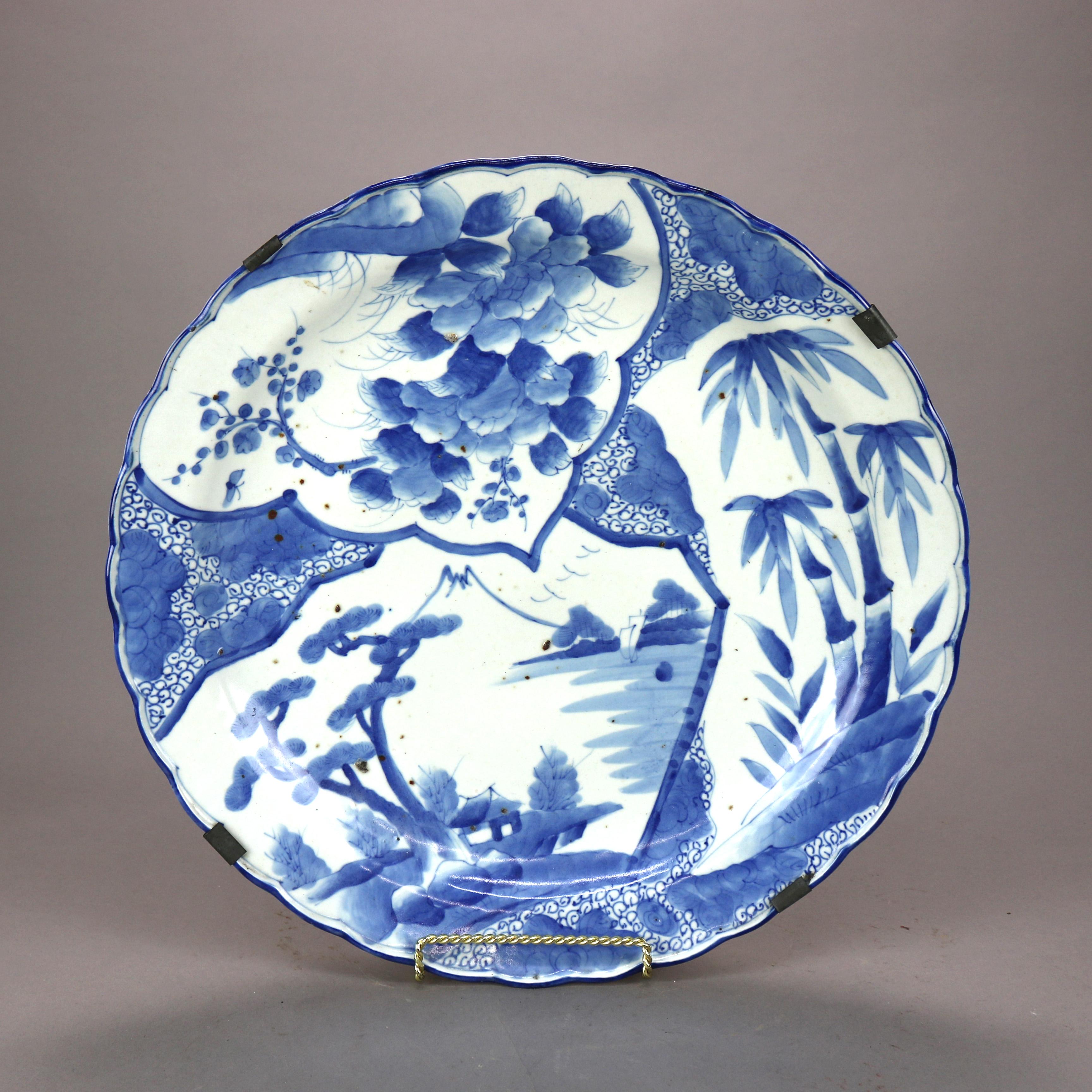 An antique and oversized Japanese Meiji charger offers porcelain construction with landscape scene in blue on white ground, en verso decoration, 19th century

Measures - 2.5'' height x 18.25'' width x 18.25'' diameter.